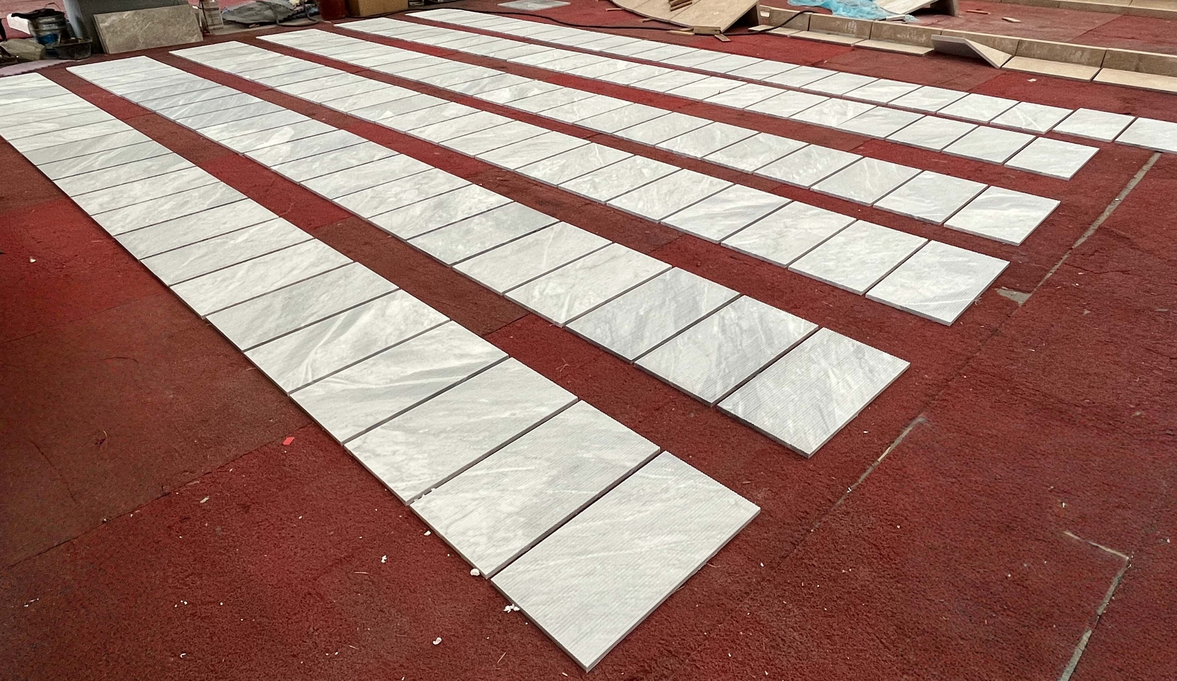 Mass layout of exclusive Carrara Gray fluted marble wall tiles, showcasing the natural stone texture and consistency in high-end production.