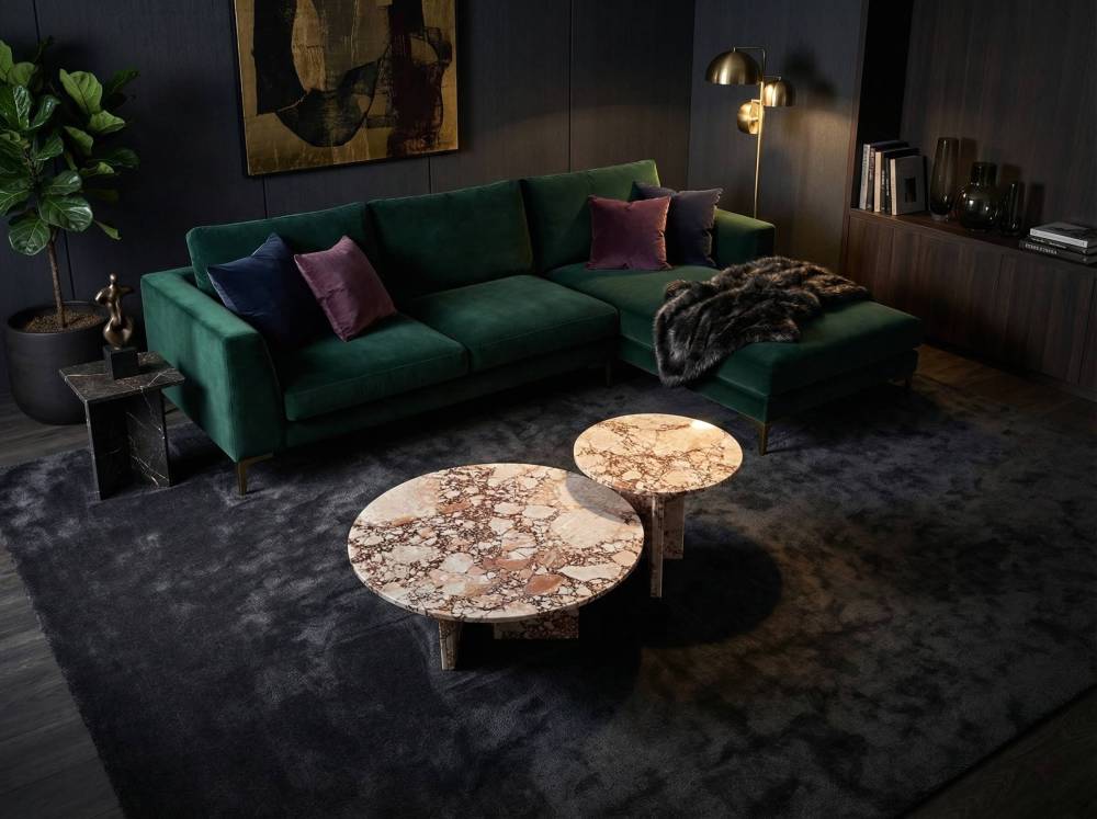 Moody dark interior design featuring a deep green velvet sofa paired with our natural pink stone nesting coffee tables. The 100% natural marble provides a striking, one-of-a-kind centerpiece.