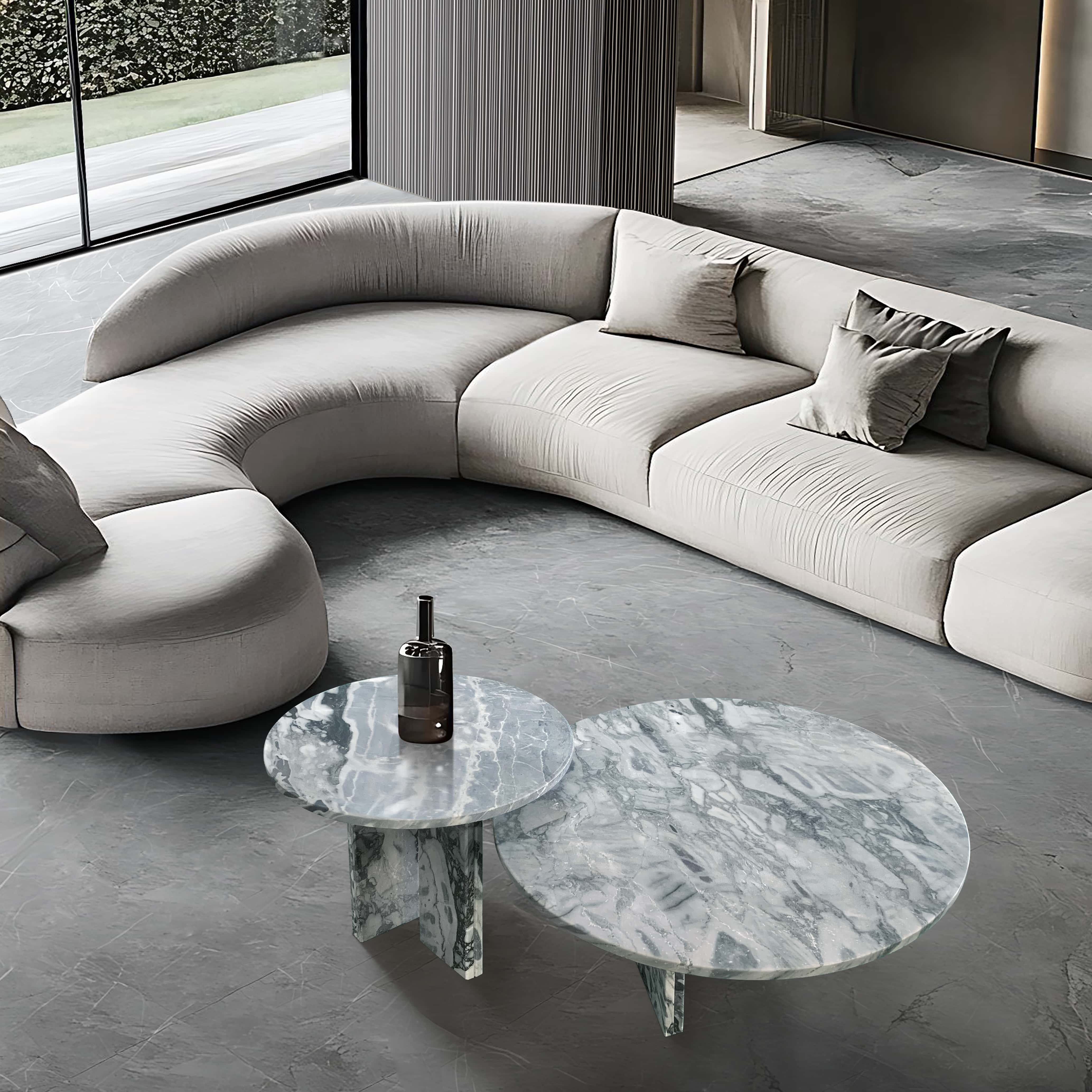 Beautiful perspective of the authentic Cloudy Blue marble coffee tables paired with a modern curved sofa, highlighting the polished, unique fluid patterns of the natural stone.