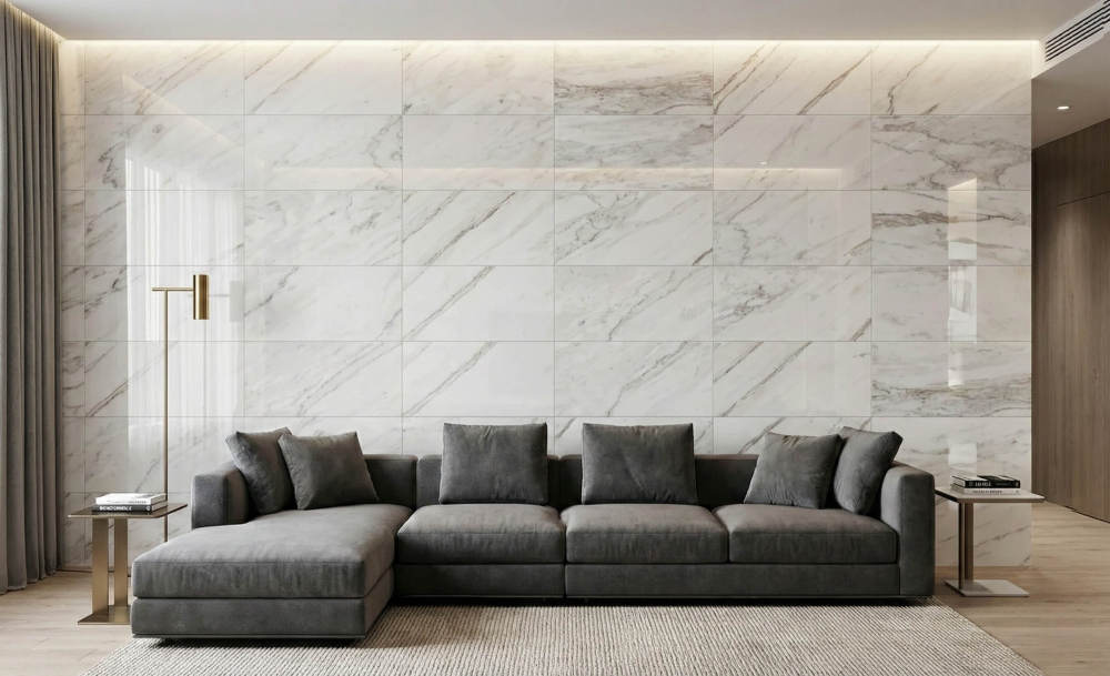 Stunning living room accent wall behind a sofa, created using polished 12x24 Snow Mountain White natural marble tiles.