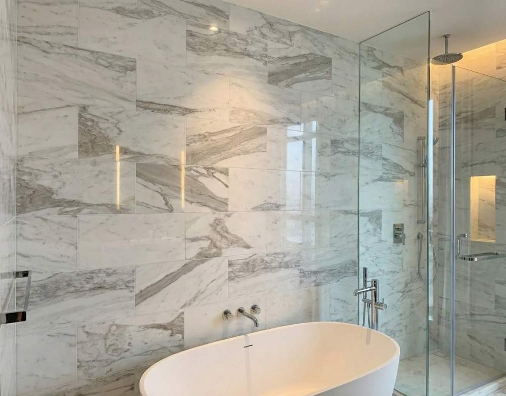 Elegant bathroom wall featuring 12x24 Snow Mountain White polished marble tiles with natural grey veining.