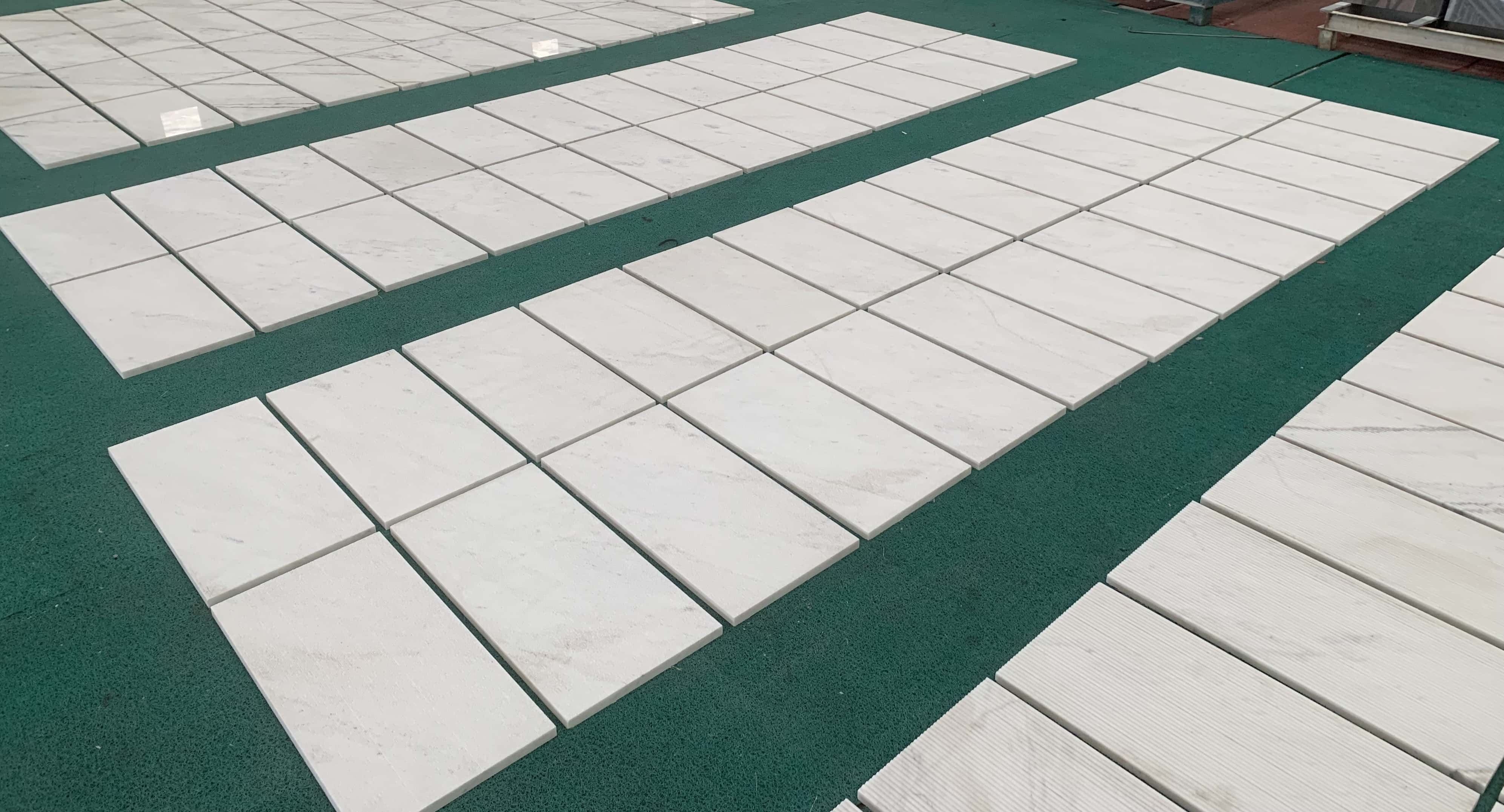 Large-scale production and layout of Snow Mountain White marble wall tiles, showing the beautiful continuity across multiple unique pieces.