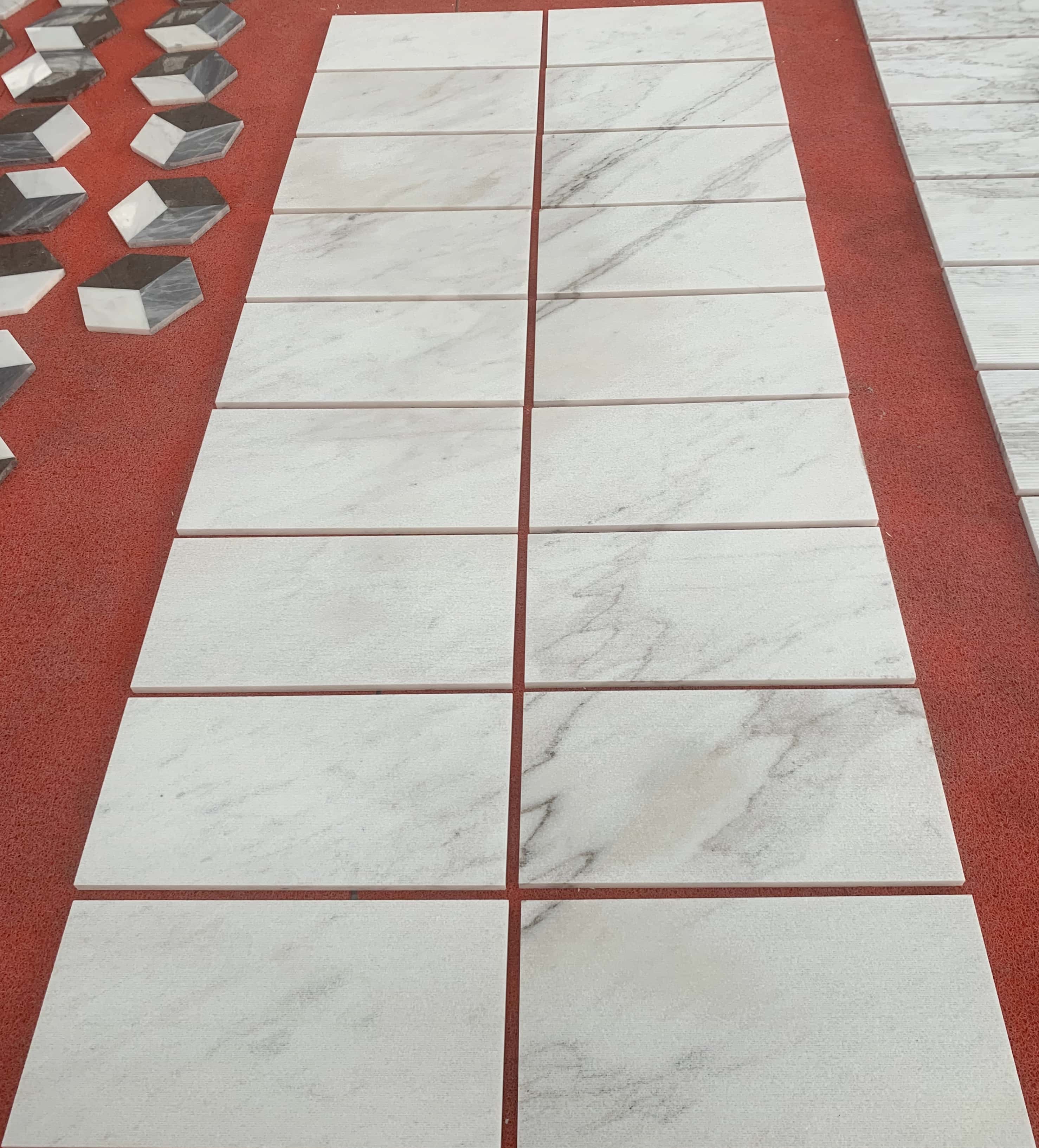 Close-up of a production batch of Snow Mountain White marble tiles, vividly displaying the exclusive natural grey veining against the textured white background.