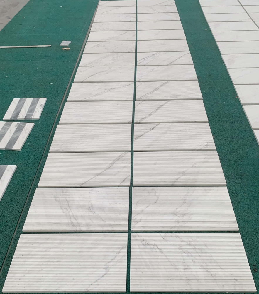 Factory bulk layout of Snow Mountain White fluted marble tiles, proving that every 100% natural stone piece is unique.