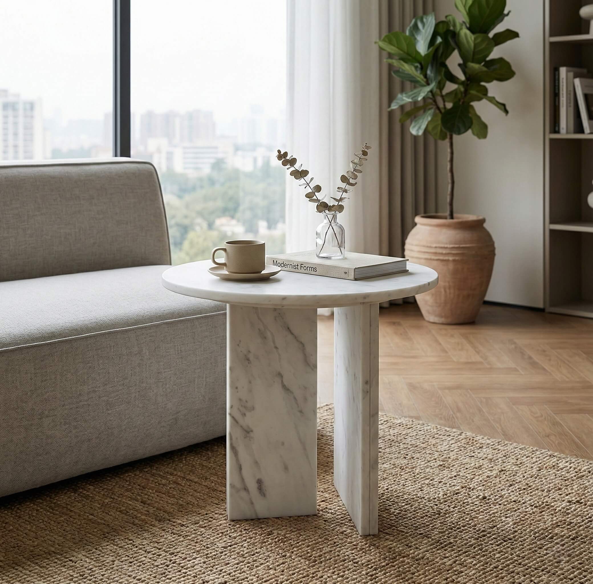Small white marble accent table next to a modern sofa against a bright city window. Each genuine stone piece is exclusive and uniquely patterned.