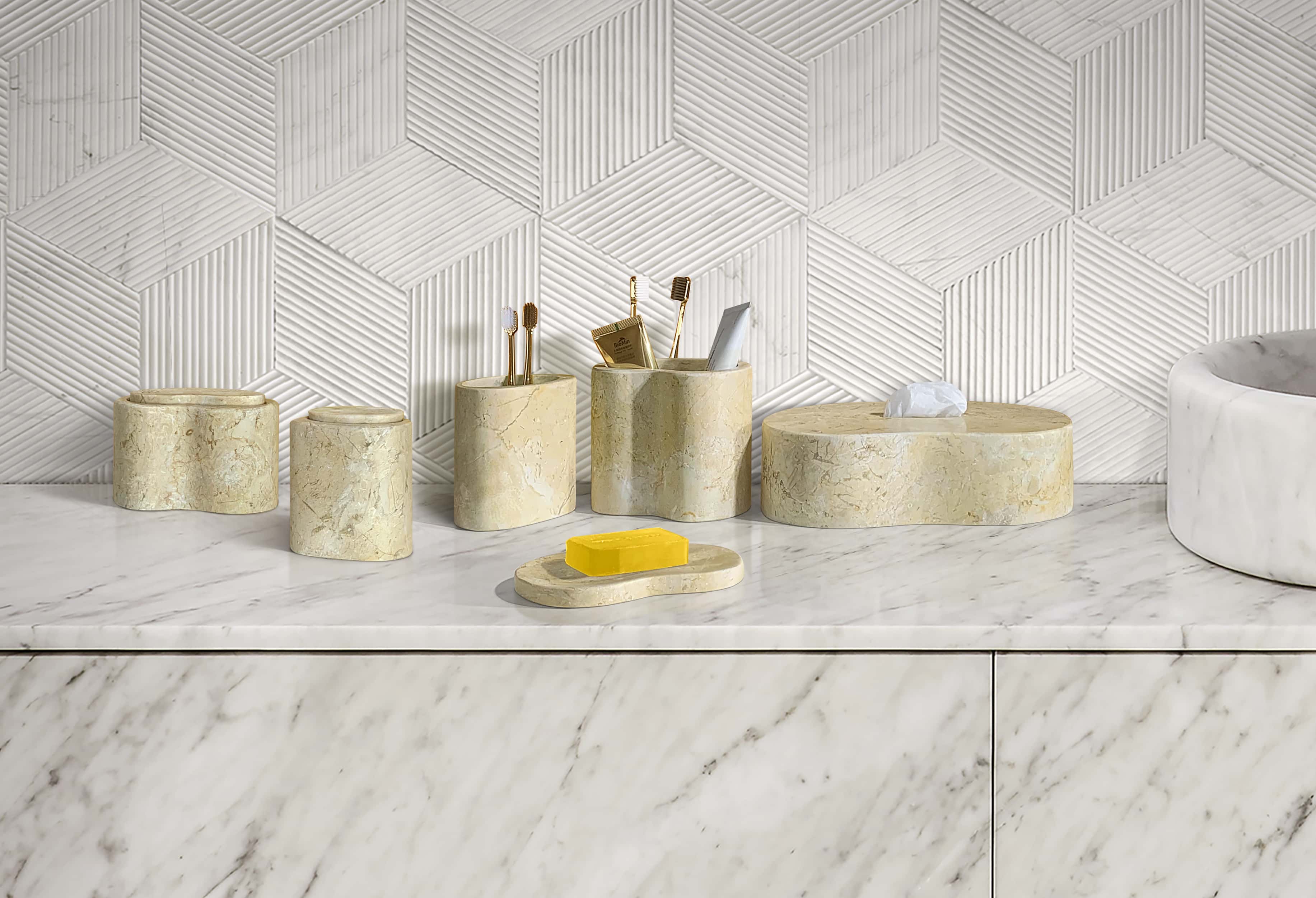 Close-up view of the 6-piece matte natural marble bathroom accessories set resting beautifully against a textured Snow Mountain White hexagonal stone wall, illustrating the premium craftsmanship and authentic natural matte finish.