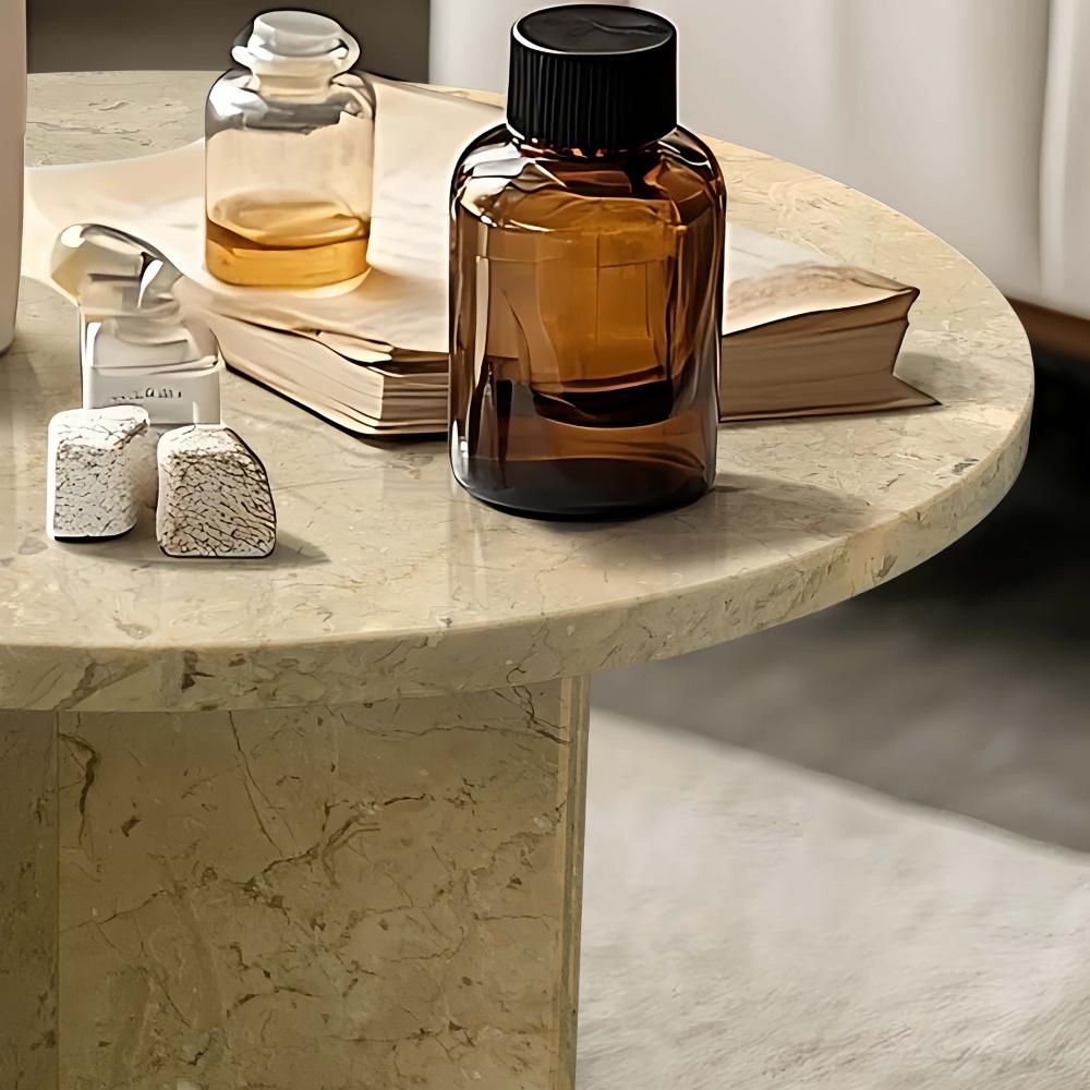 Detail shot of the Hyatt Gold natural stone coffee table surface reflecting amber glass decor. Highlights the premium polished finish of the exclusive marble material.
