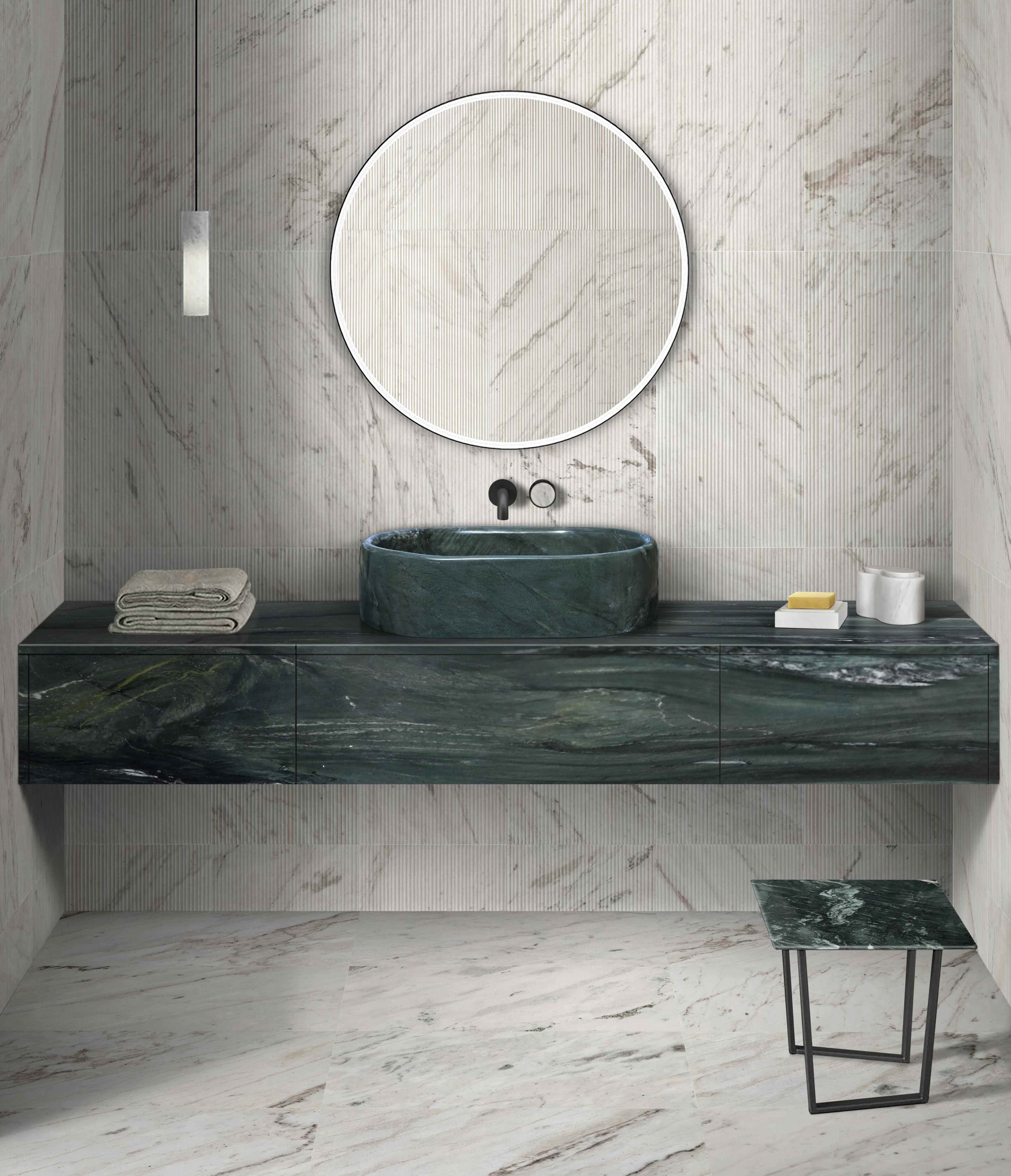 A polished oval green marble vessel sink styled on a green marble vanity. The background features Snow Mountain White textured wall tiles with linear patterns and 12x24 polished floor tiles, complemented by marble bathroom accessories.