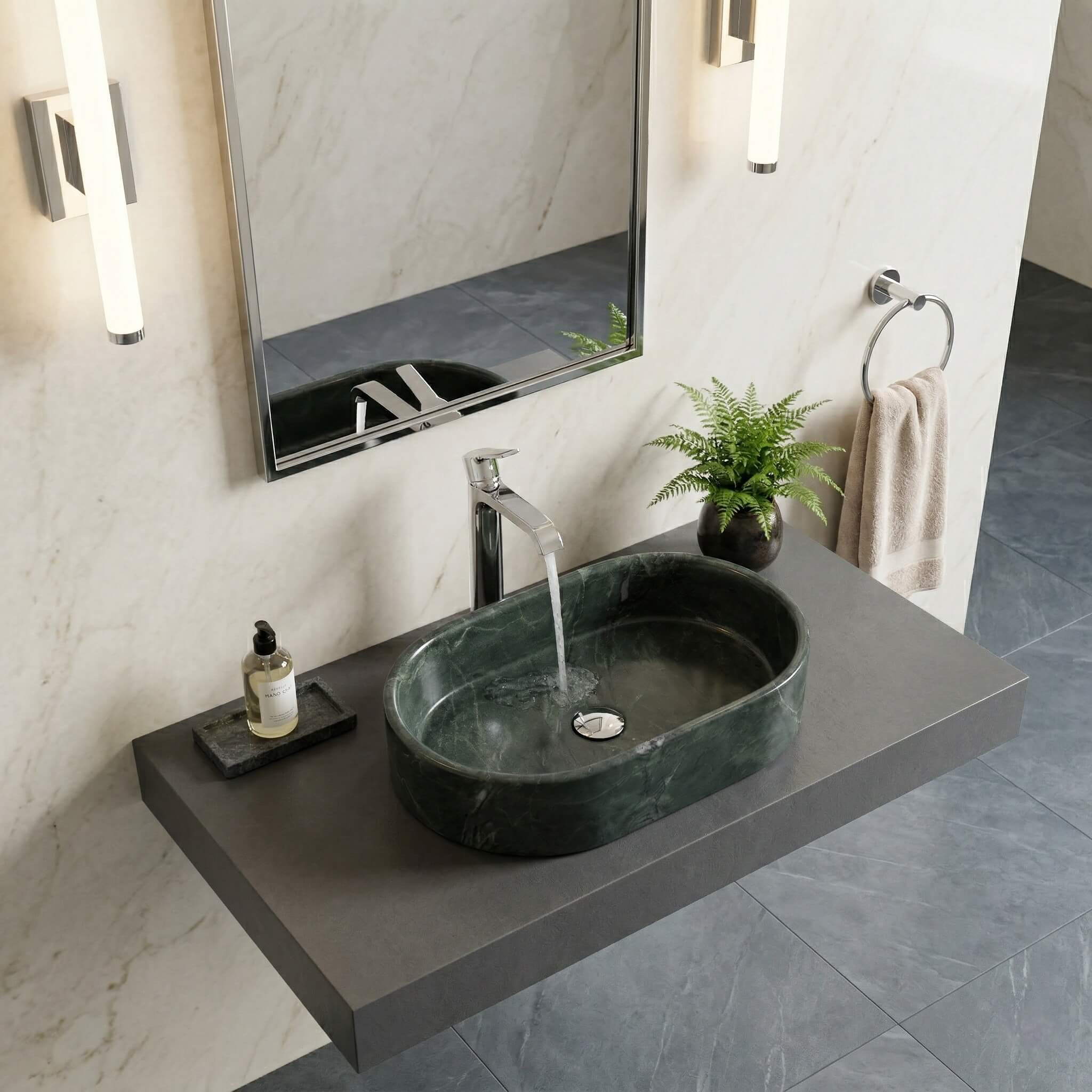 Angled lifestyle view of a polished dark green marble above-counter sink featuring white natural veining, sitting on a modern bathroom counter.