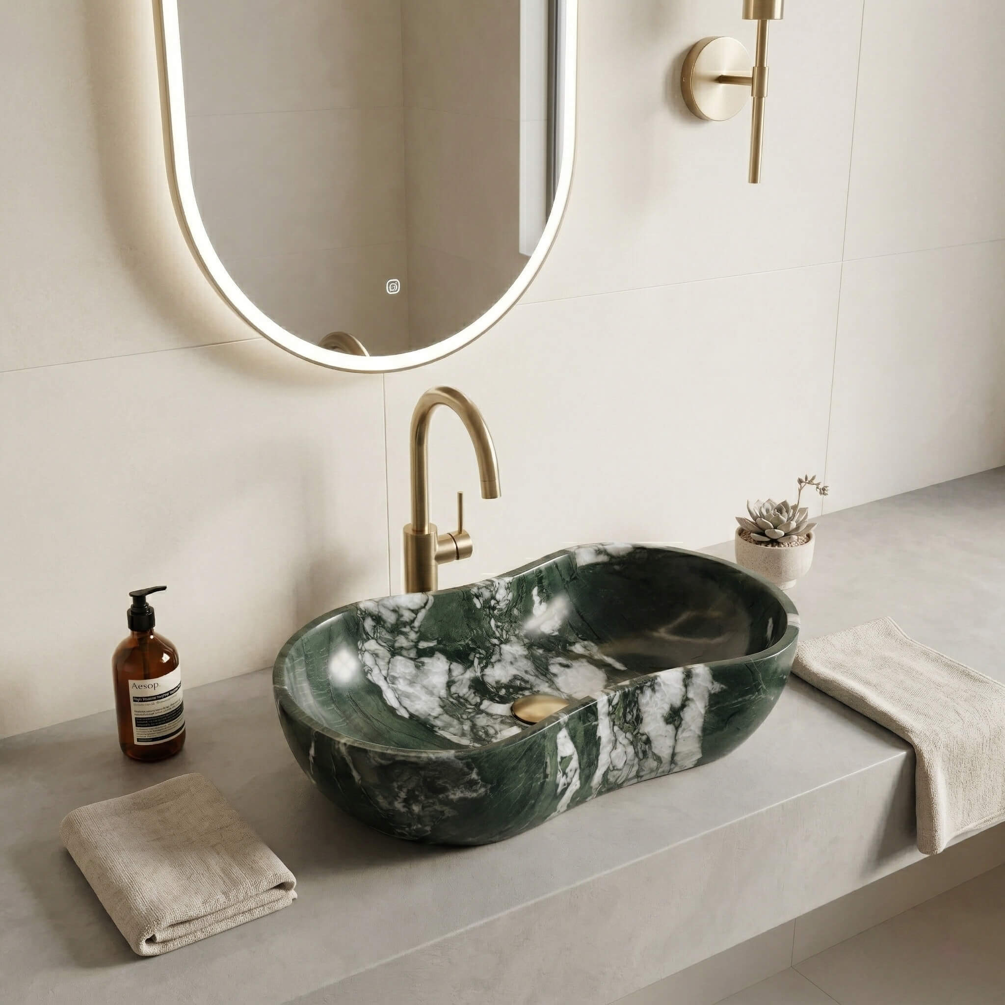 Dramatic white-veined Diamond Green marble sink on a grey concrete vanity, featuring a brushed gold gooseneck faucet and a backlit oval mirror in a high-end master bathroom.