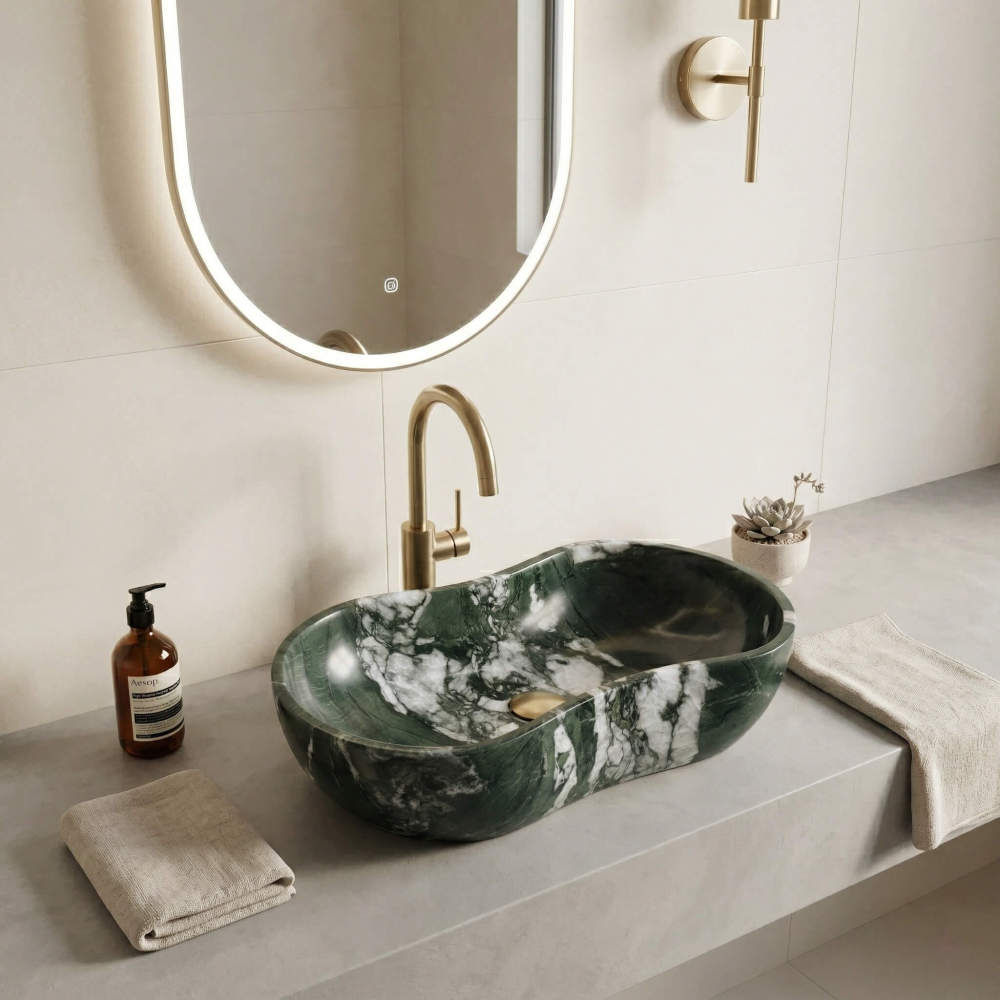 Dramatic white-veined Diamond Green marble sink on a grey concrete vanity, featuring a brushed gold gooseneck faucet and a backlit oval mirror in a high-end master bathroom.