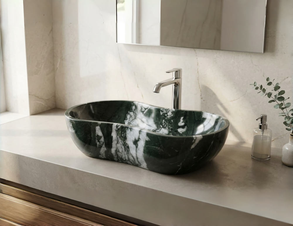 One-piece carved Diamond Green marble vessel sink with high-contrast white veining, paired with a polished chrome faucet on a neutral stone countertop under bright natural lighting.