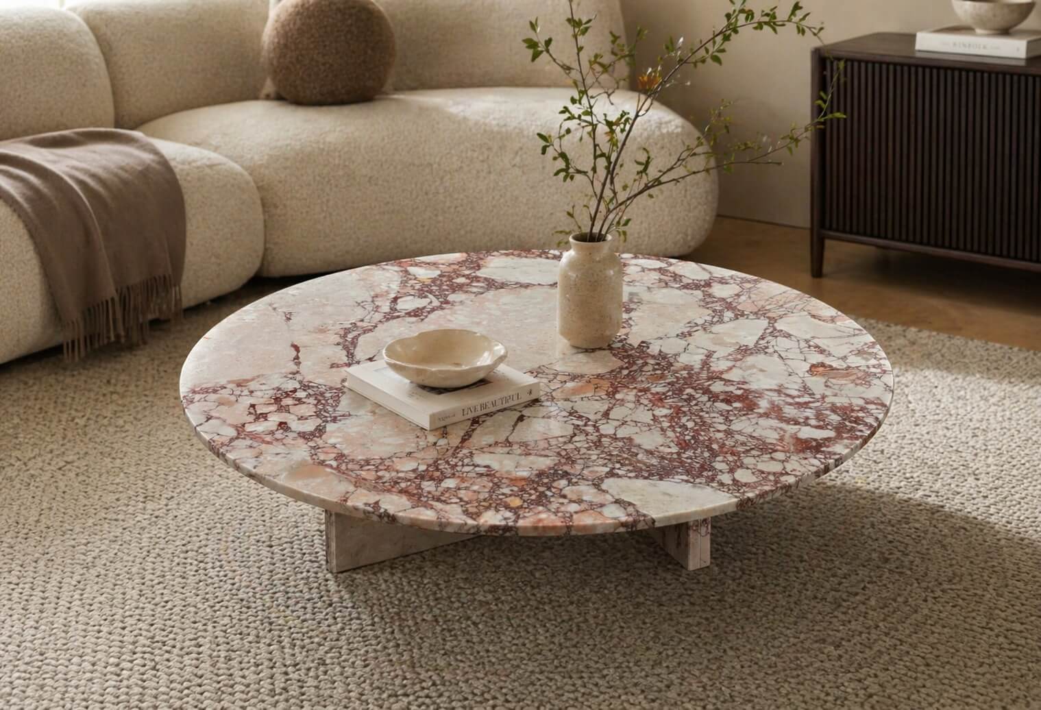 Low-profile Diamond Pink marble coffee table paired with a cream bouclé sofa and woven jute rug in an organic modern interior.