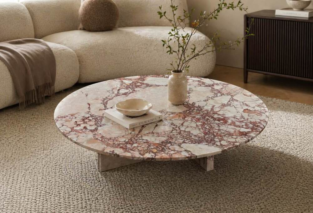 Low-profile Diamond Pink marble coffee table paired with a cream bouclé sofa and woven jute rug in an organic modern interior.