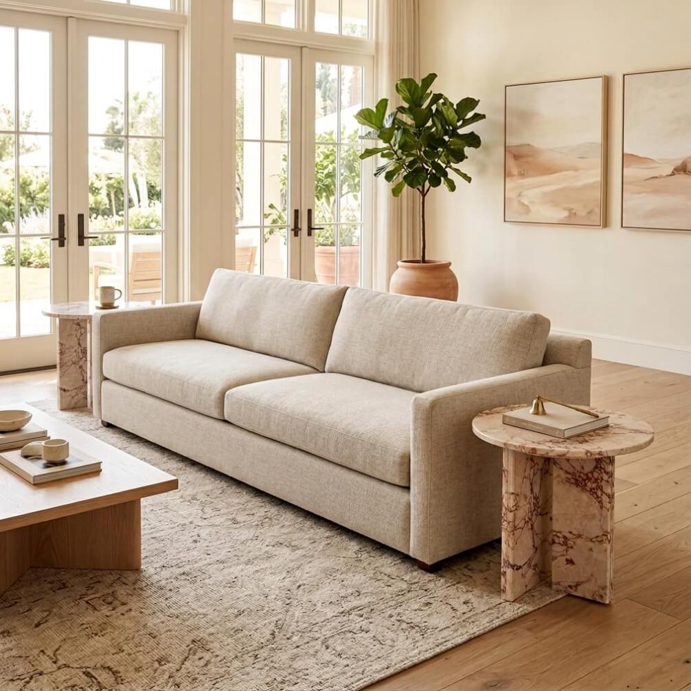 Two Diamond Pink marble side tables paired with a low natural wood coffee table in a California modern living room — sand-tone linen sofa, French doors with garden view, fiddle leaf fig in terracotta pot, desert landscape watercolor art on wall.