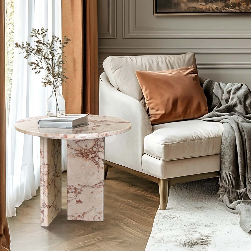 Diamond Pink marble round side table beside a cream linen accent chair in a French transitional living room with deep sage green panel molding walls — herringbone oak floor, copper velvet cushion, dried branch arrangement in glass vase on polished natural stone surface.