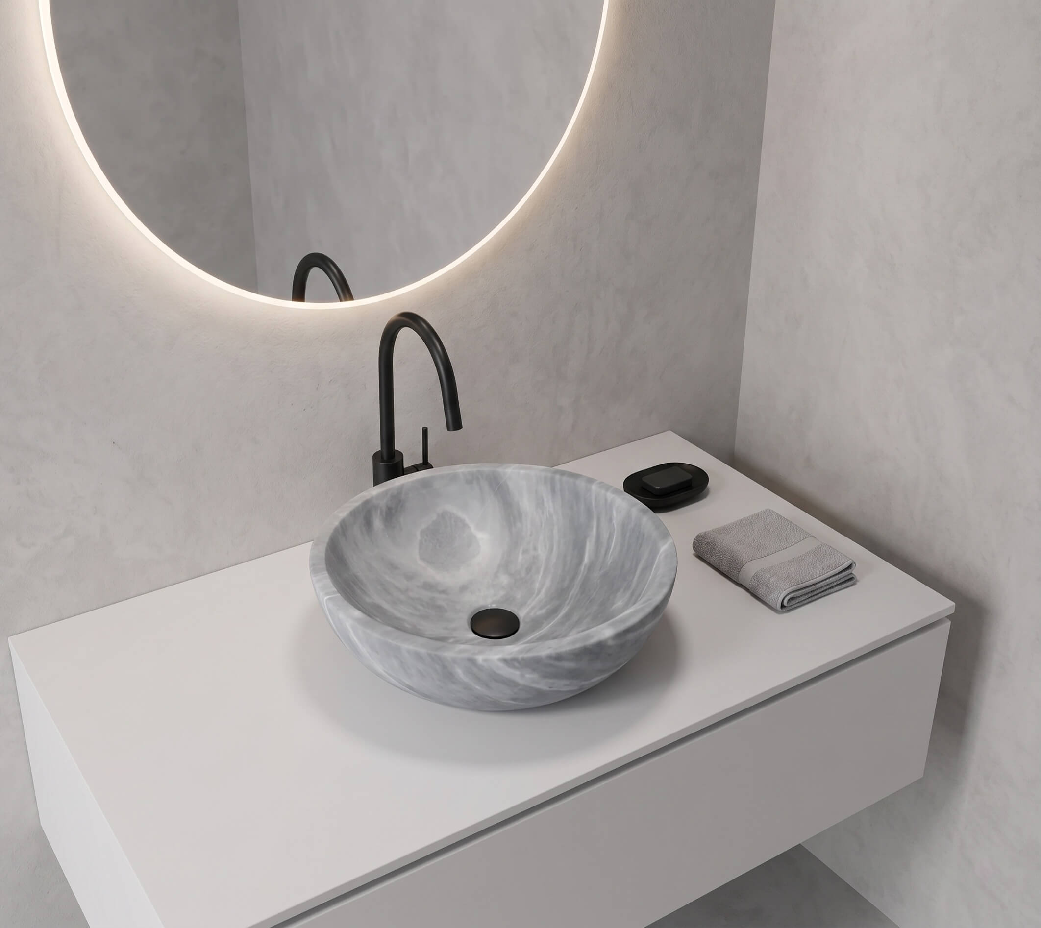 Single Carrara gray marble round vessel sink as sculptural focal point on a pure white handle-less floating vanity, matte black gooseneck faucet, halo-lit round mirror with backlit LED ring, textured white plaster wall, minimal styling with single black marble soap dish, gallery-aesthetic bathroom.