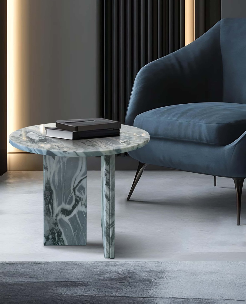 Cloudy blue marble side table next to navy velvet armchair in modern luxury lounge with vertical wood paneling and accent lighting.
