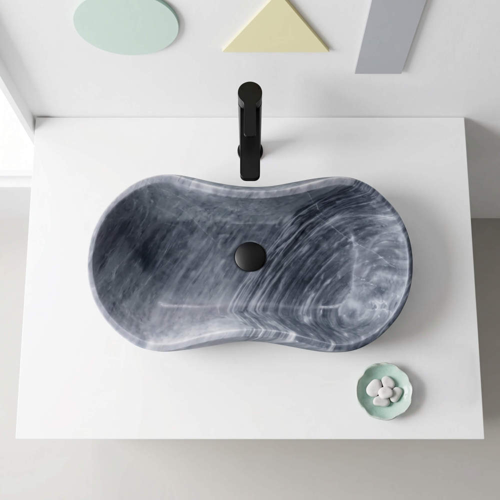Overhead view of Carrara gray marble vessel sink on white counter with matte black wall-mount faucet in a Memphis postmodern geometric bathroom.