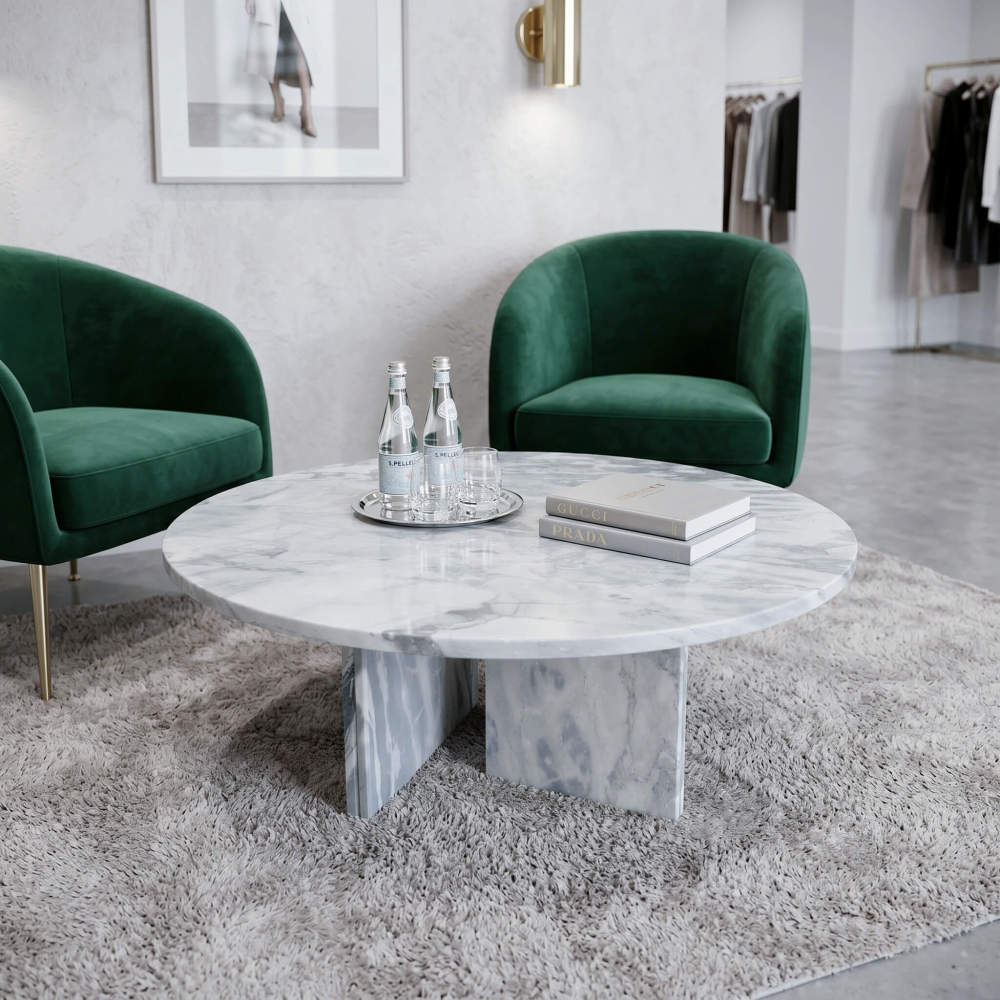 Cloudy blue marble coffee table in boutique fashion lounge with emerald velvet armchairs, designer art books, and curated retail display.
