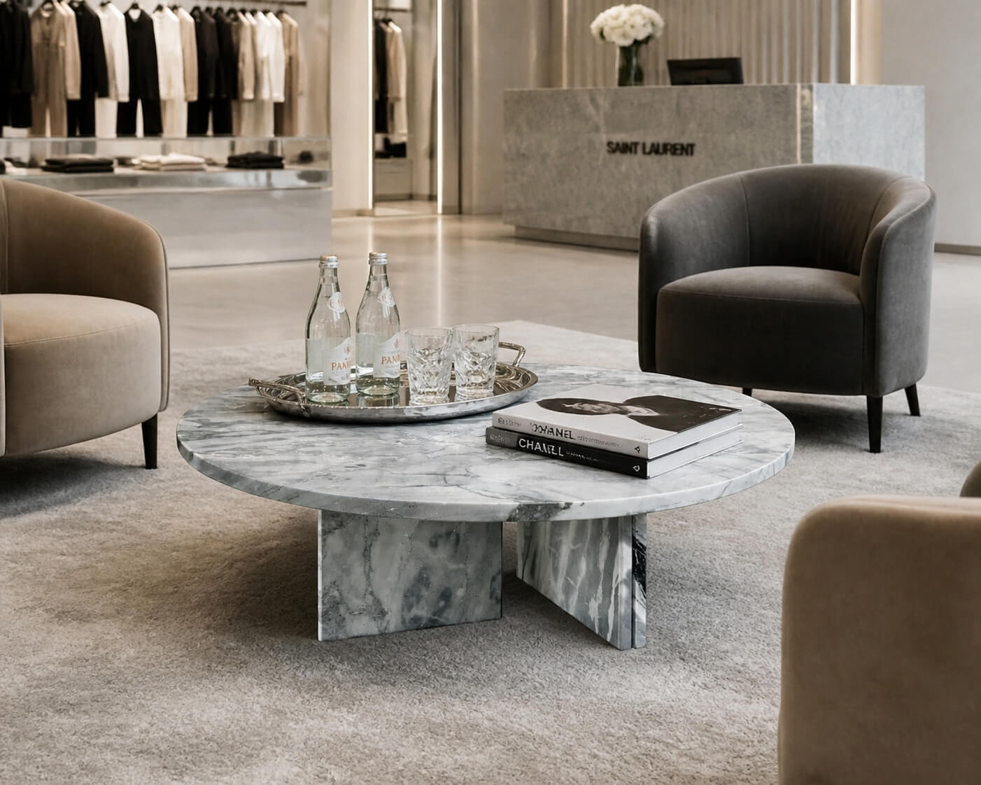 Cloudy blue marble coffee table styled in luxury retail lounge with velvet armchairs, silver tray service, and designer fashion books.