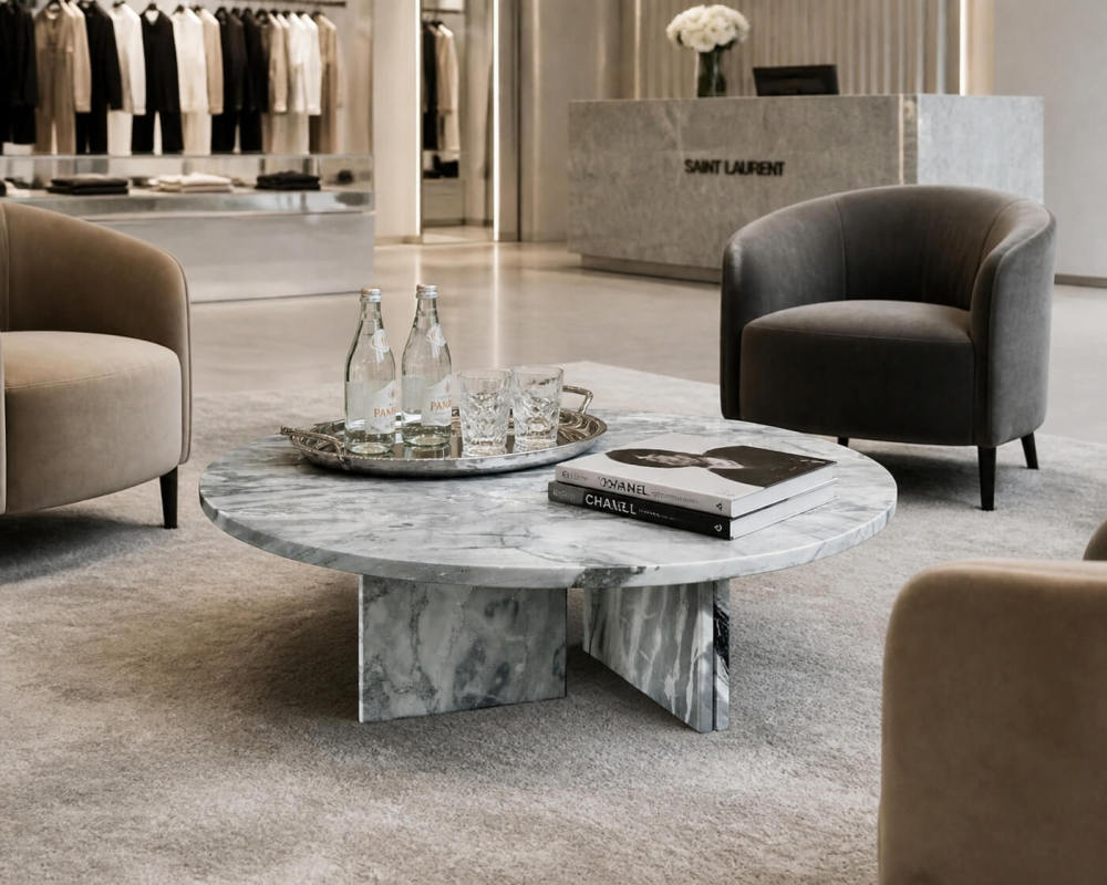 Cloudy blue marble coffee table styled in luxury retail lounge with velvet armchairs, silver tray service, and designer fashion books.