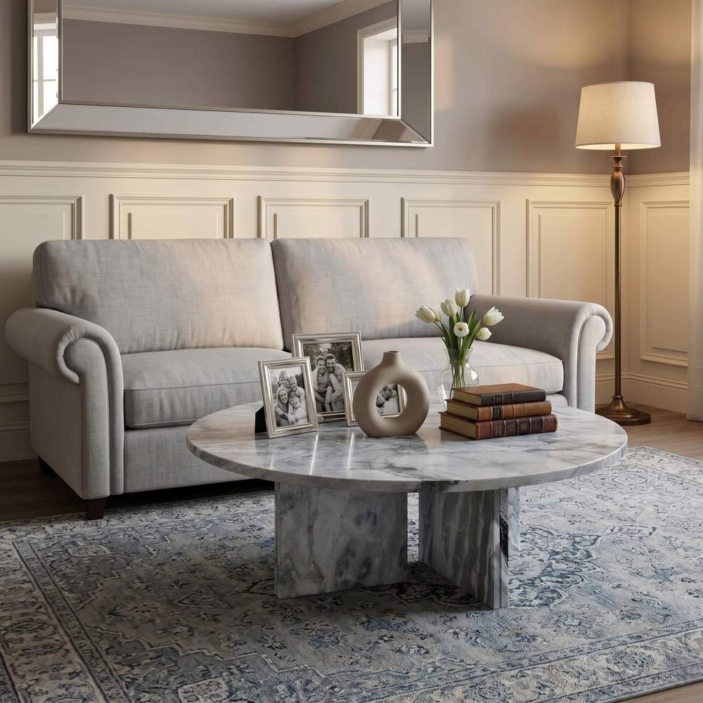 Cloudy blue marble coffee table in traditional living room with linen sofa, silver-framed photos, white tulips, and wainscoting.