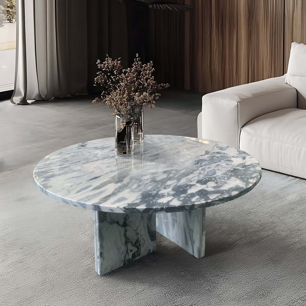 Cloudy blue marble coffee table in contemporary living room with white linen sofa, glass vase of dried branches, and walnut accent wall.