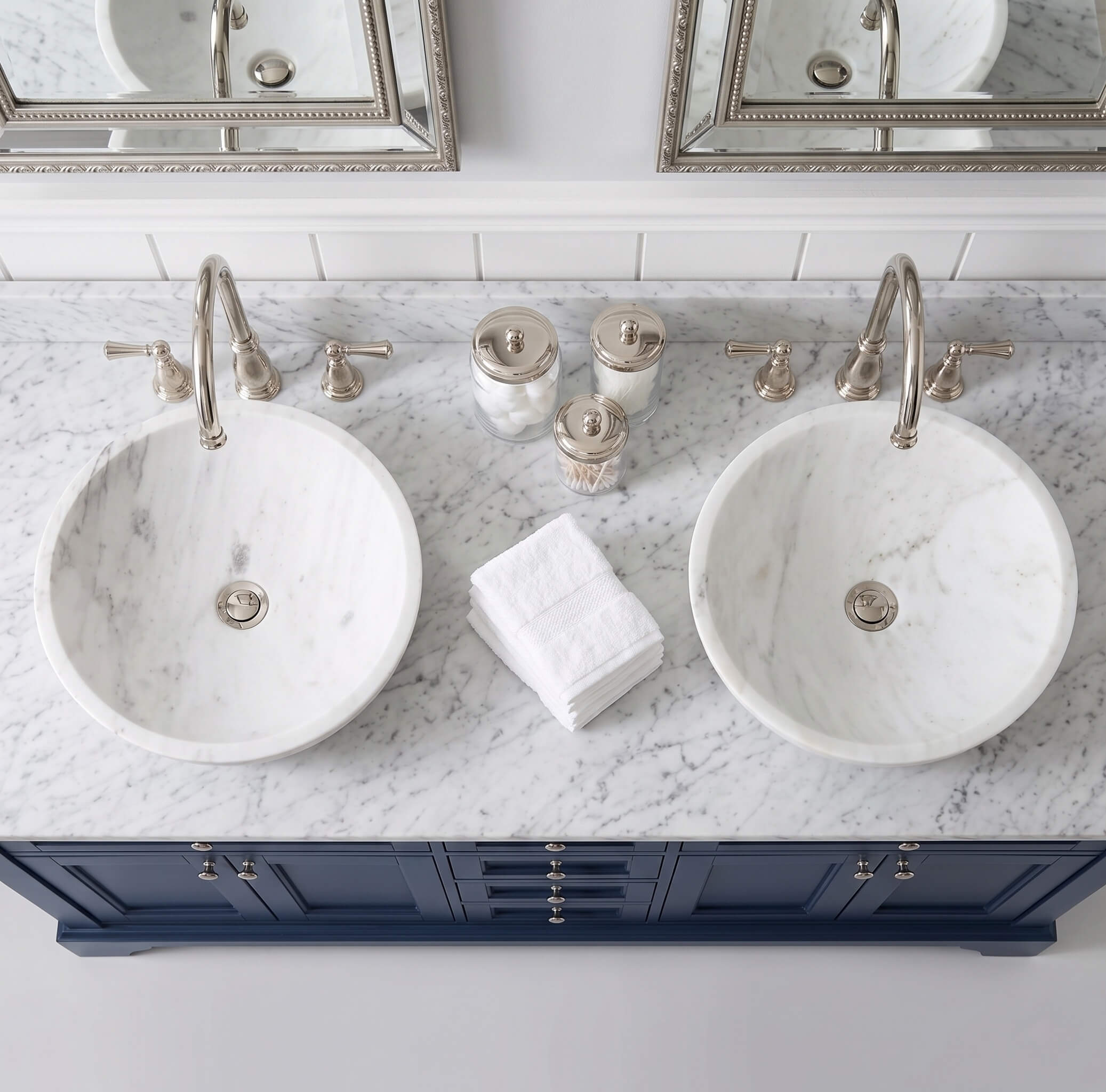 Snow Mountain white marble vessel sinks on Carrara top, navy cabinetry, polished nickel faucets, Hampton-style bathroom.