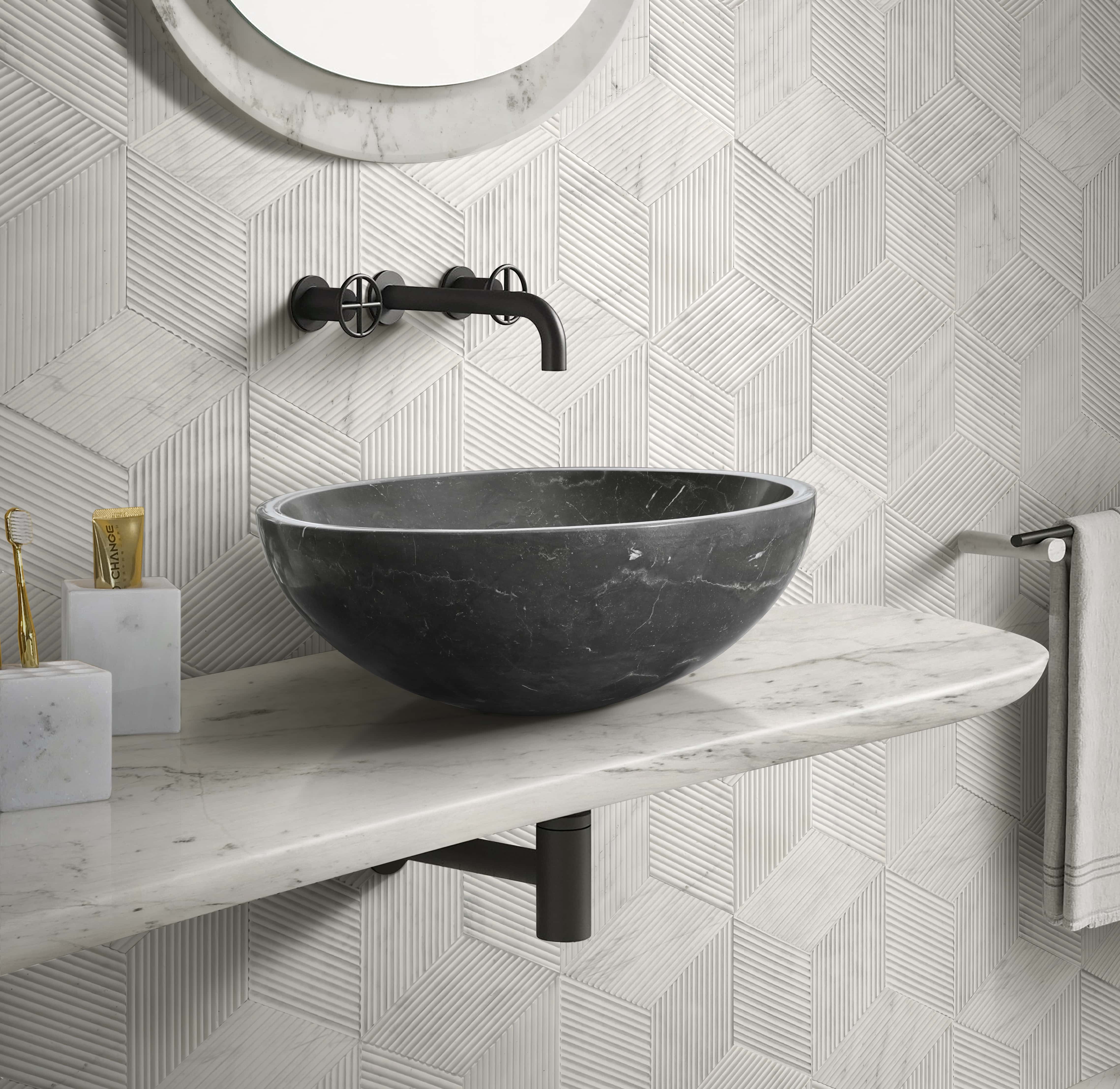 Black marble vessel sink with hexagon textured wall tile and matching white marble accessories in coordinated bathroom set.