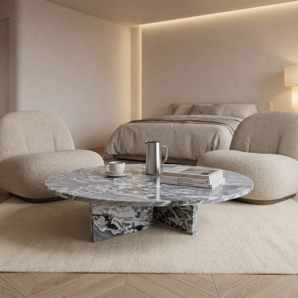 Cloudy blue marble coffee table in quiet luxury bedroom sitting area with boucle armchairs and herringbone wood floor.