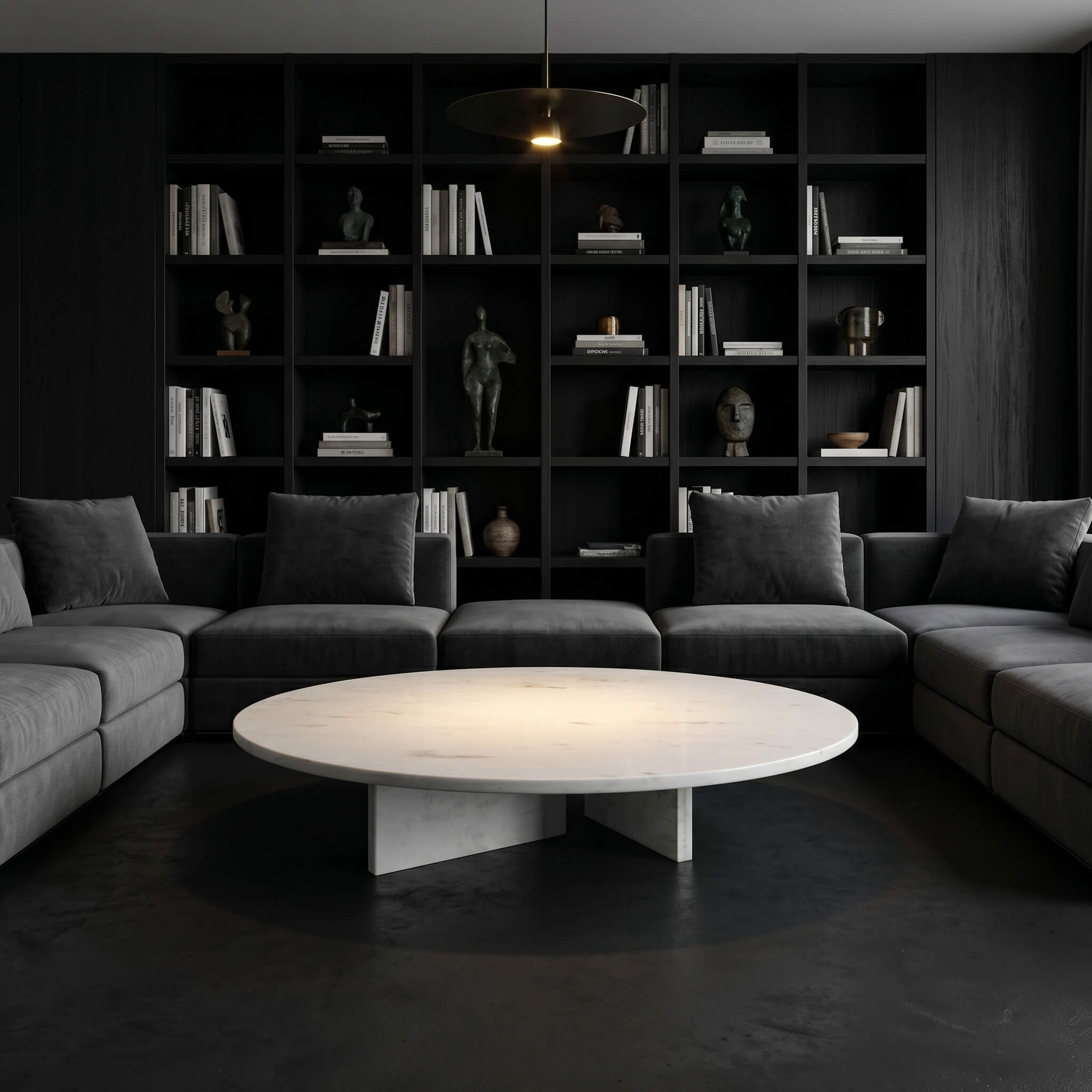 Round white marble coffee table in a dark library lounge with grey sectional sofa and black sculpture shelving.