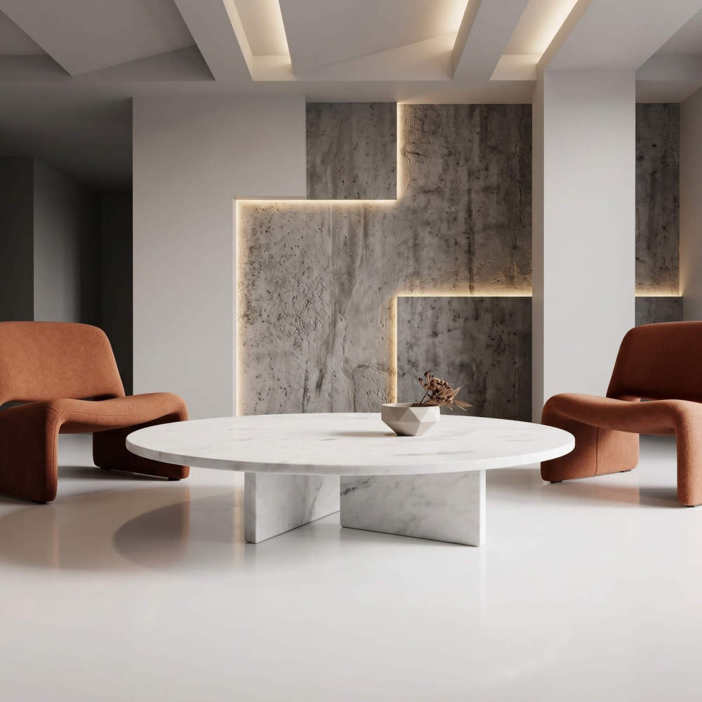 Round white marble coffee table in a minimalist room with rust bouclé armchairs and a backlit concrete feature wall.
