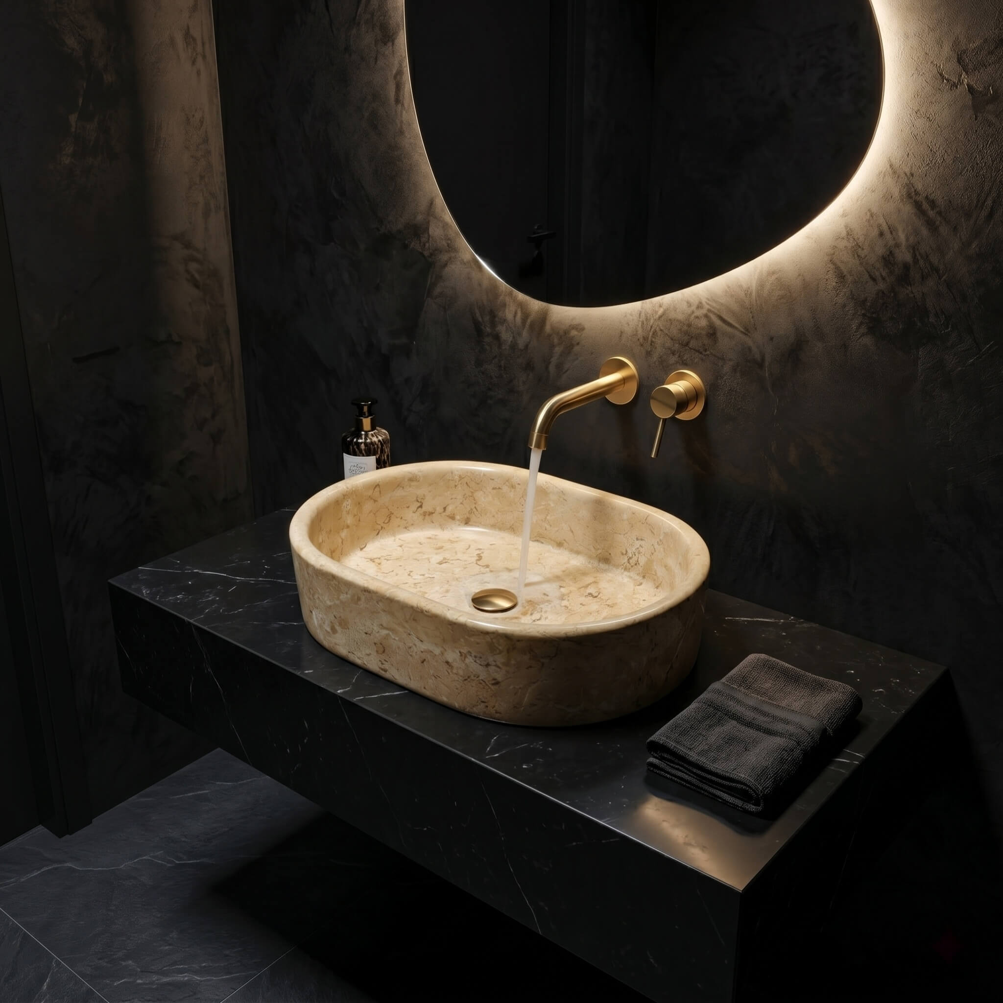Amber Gold marble vessel sink on black marble shelf with brass wall-mount faucet and running water, glowing moon mirror, dark moody bathroom.