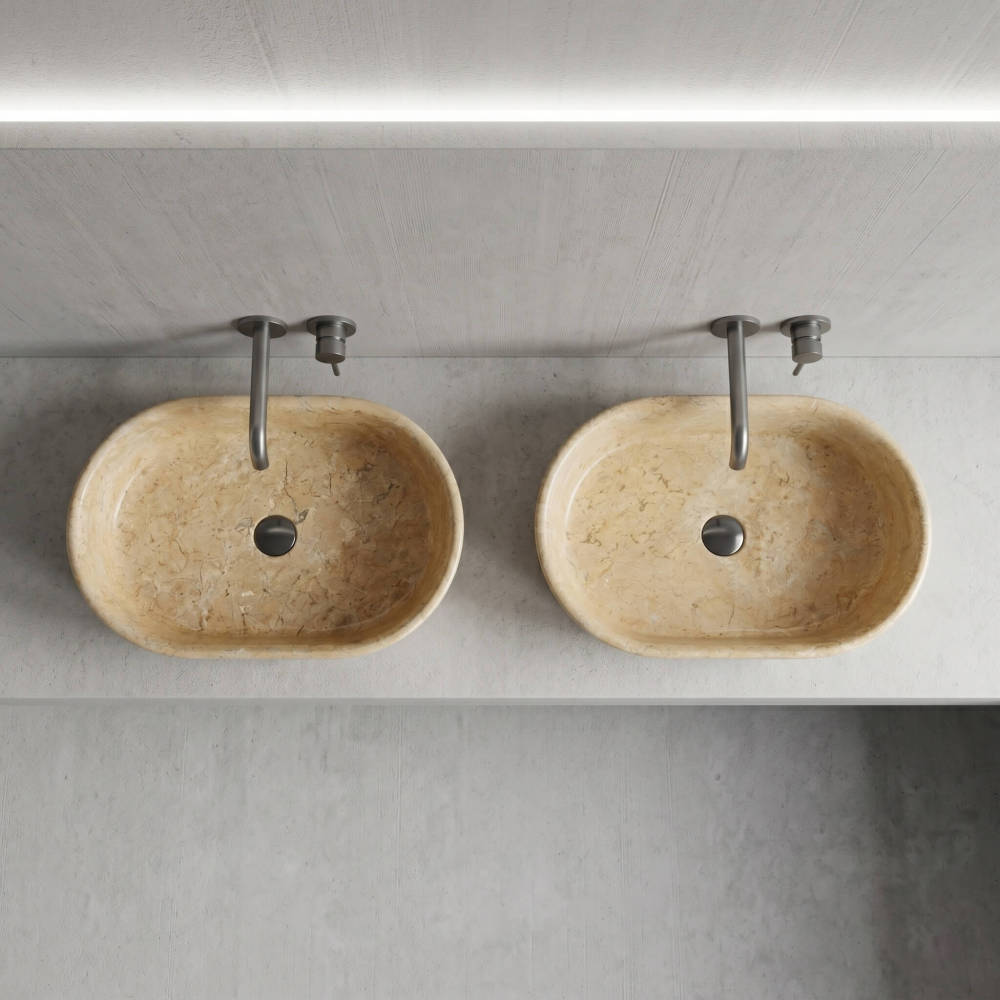 Overhead view of two Hyatt Gold marble vessel sinks on gray vanity, showing natural veining variation between individual units, matte faucets.