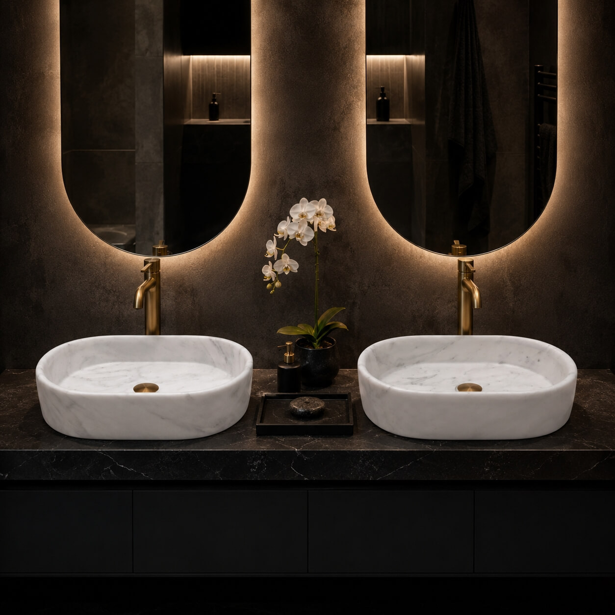 Two Snow Mountain White marble oval vessel sinks on a black countertop with brushed gold faucets and backlit mirrors in a dark, dramatic modern bathroom.