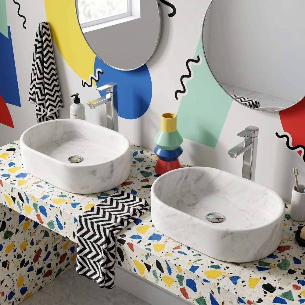 Two Snow Mountain White marble oval vessel sinks on a colorful terrazzo ledge with chrome faucets and squiggle wall art in a playful Memphis postmodern bathroom.