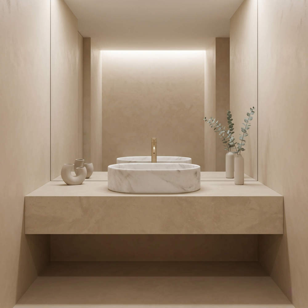 A Snow Mountain White marble oval vessel sink centered on a plaster floating ledge with champagne gold faucet and eucalyptus in a serene minimalist spa bathroom.