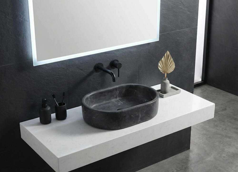 An Olive Black marble oval vessel sink on a white quartz top against a dark slate tile wall with a black wall-mounted faucet.