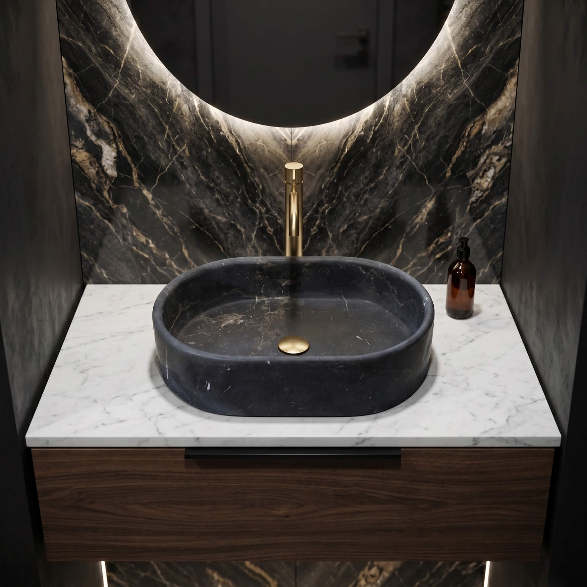 An Olive Black marble oval vessel sink on a walnut vanity below a backlit mirror, set against a dramatic veined stone wall.