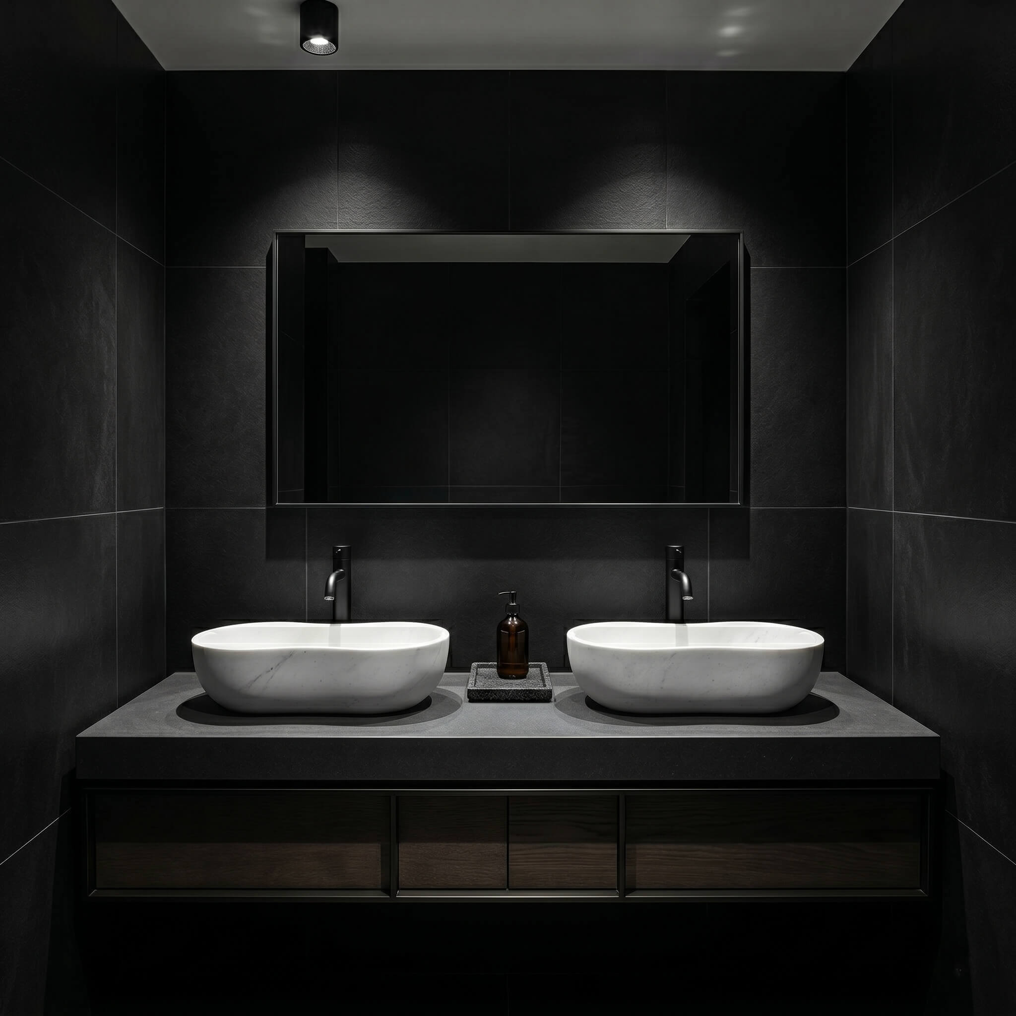 Symmetrical layout of two white wavy marble vessel sinks on a thick dark grey concrete floating vanity with dark walnut drawers against a large-format matte black stone tile wall.