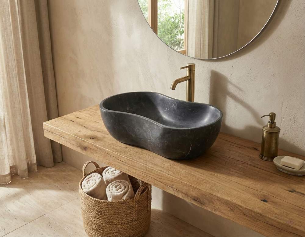 A single honed Olive Black natural marble wave vessel sink styled with a brushed gold faucet on a thick, rustic organic wood slab floating vanity.