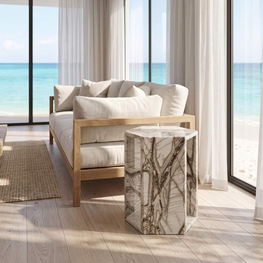 Arboris White marble hexagon side table in a sunlit coastal living room with floor-to-ceiling ocean views.