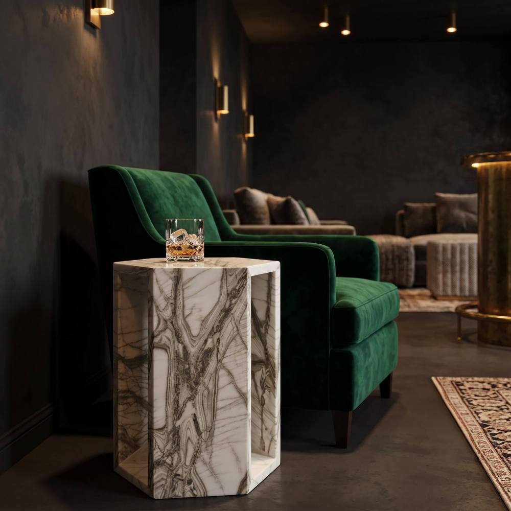 Arboris White marble hexagon end table holding a whiskey glass next to an emerald green velvet armchair.