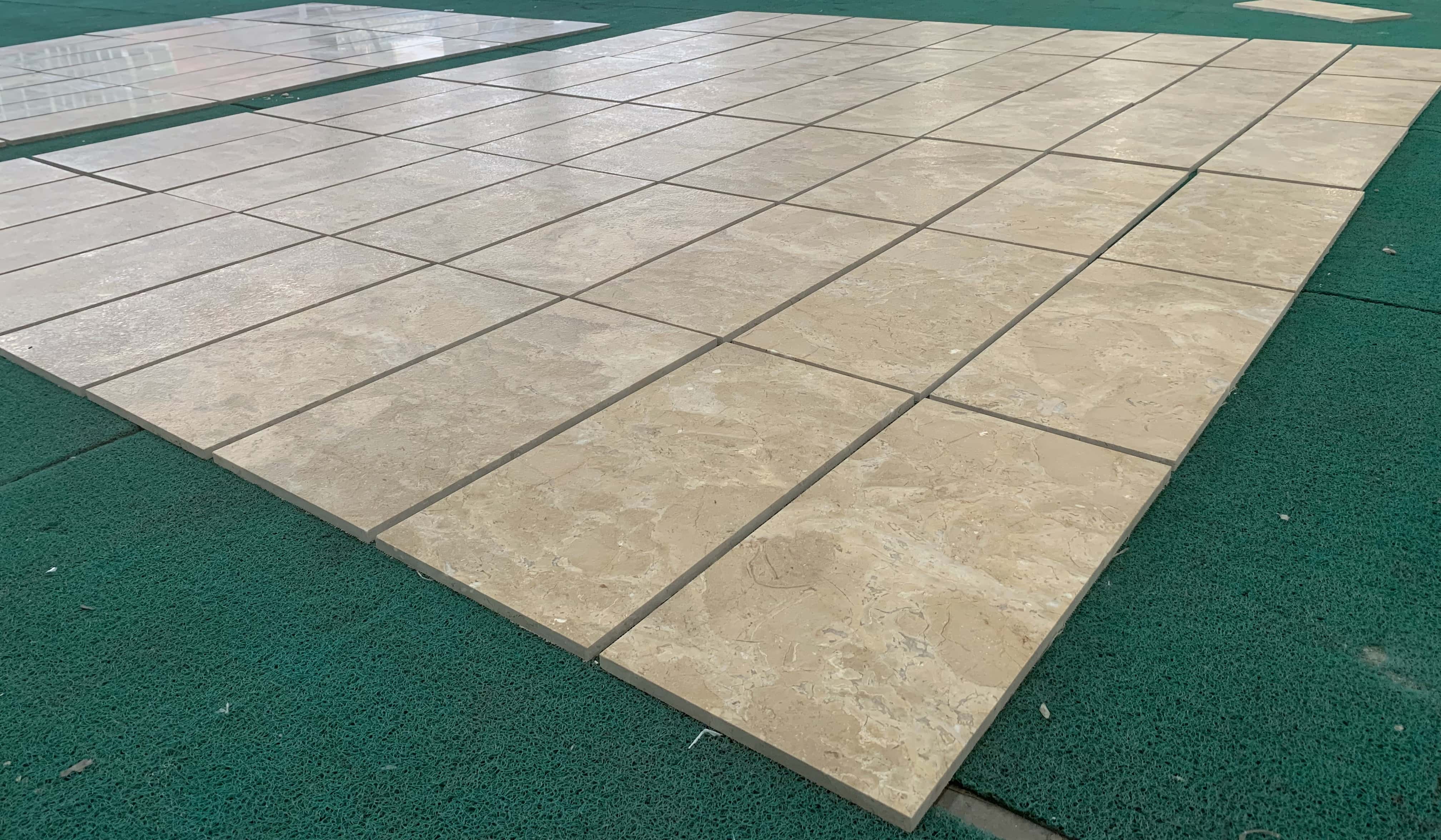 Perspective view of batch-produced Amber Gold marble tiles laid out during quality control to check consistency and tone.
