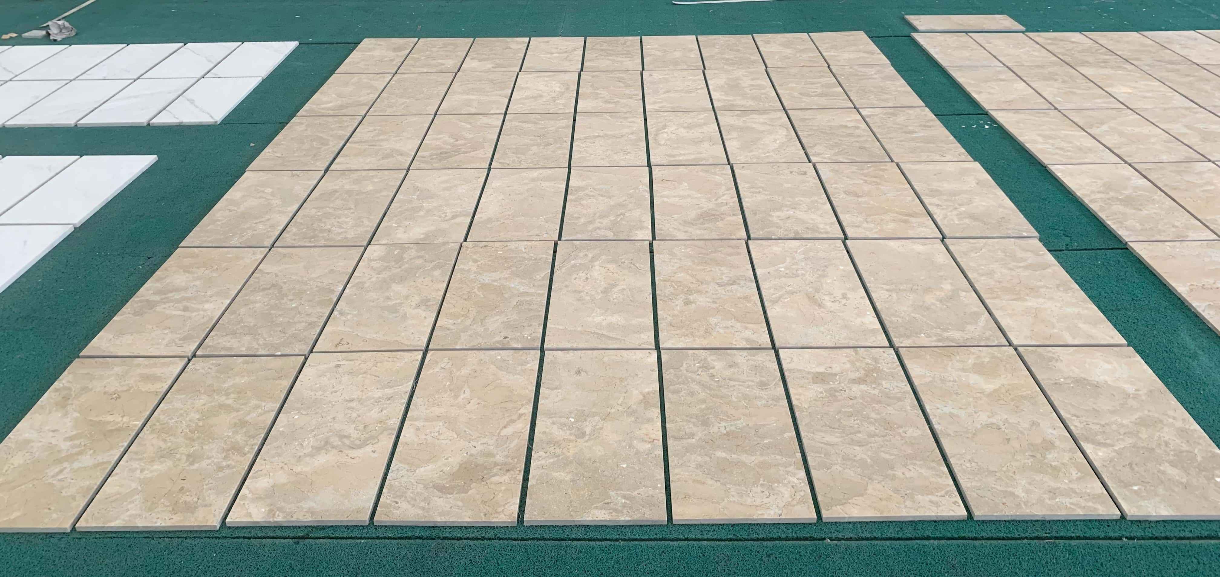 Factory quality inspection layout showing multiple rows of 12x24 Amber Gold natural marble tiles arranged for batching.