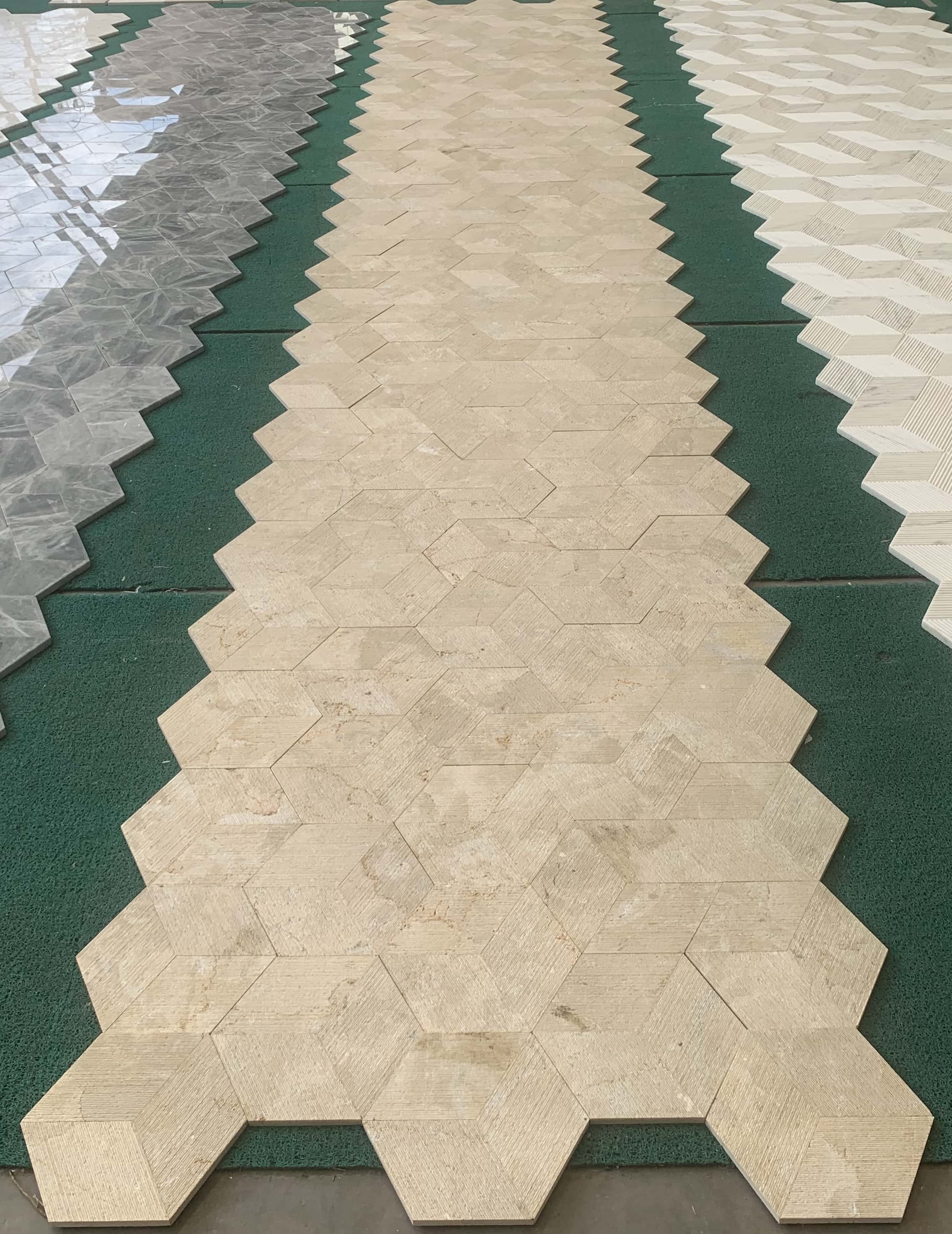 Extended factory dry-lay inspection showing color consistency across multiple Amber Gold natural marble hexagon wall tiles.