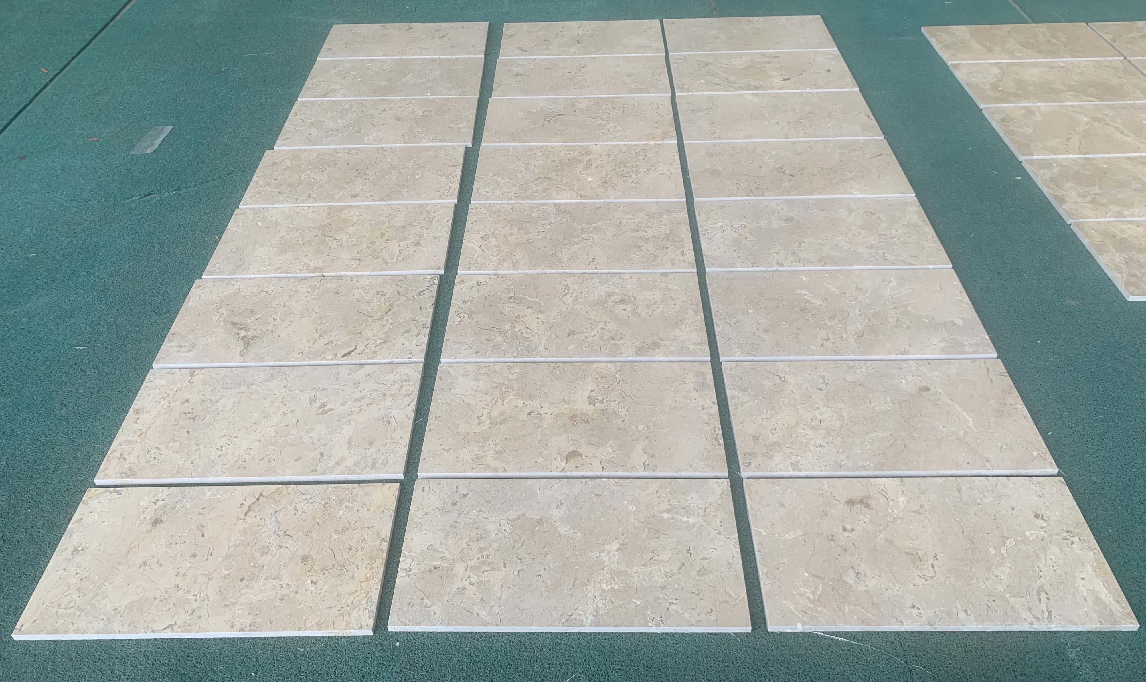 A large field dry lay of numerous 12x24 Amber Gold honed marble tiles, demonstrating color blending across an extensive area.