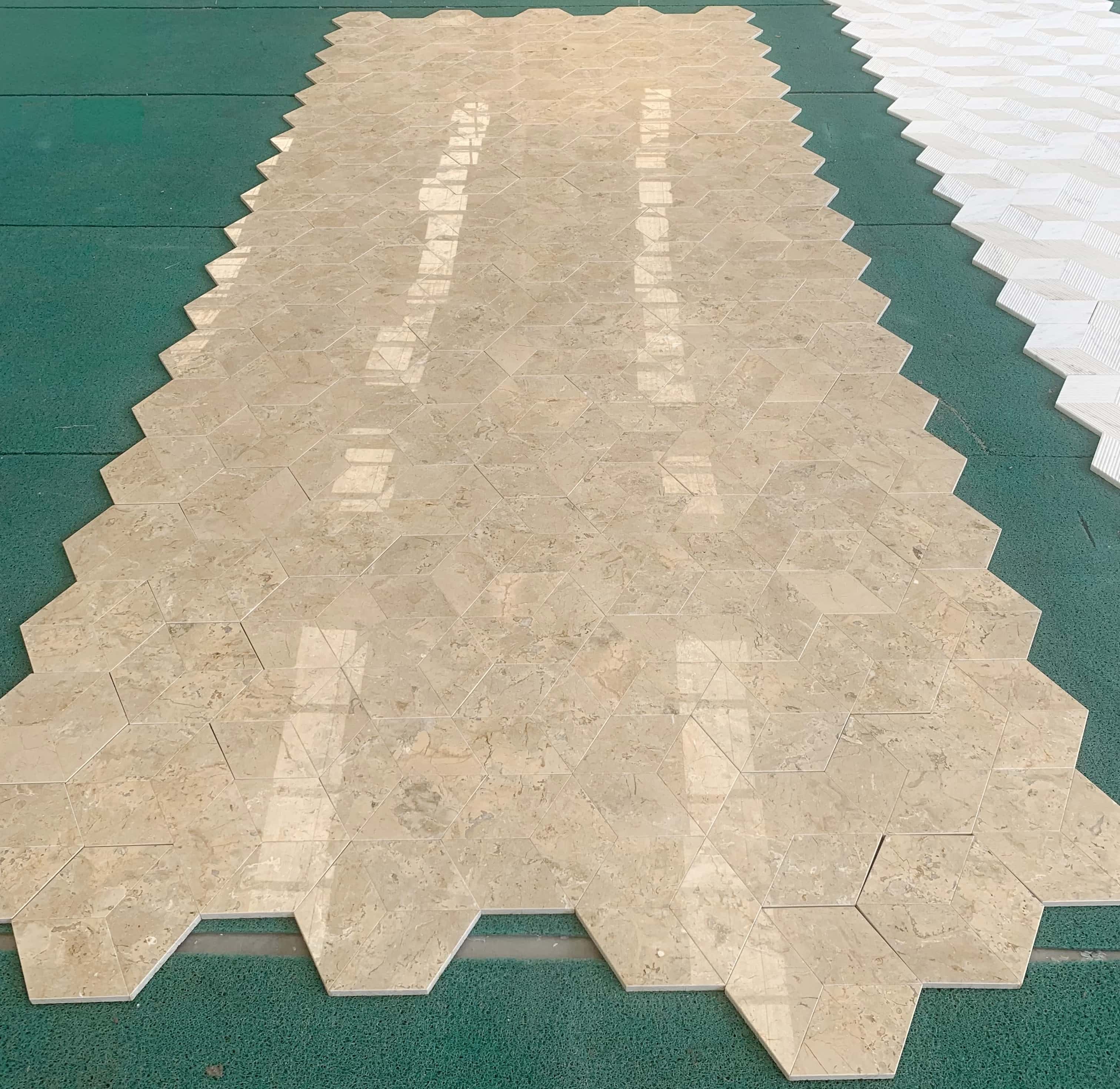 Large-scale factory floor layout of polished Amber Gold marble hexagon tiles reflecting light across a continuous grid.
