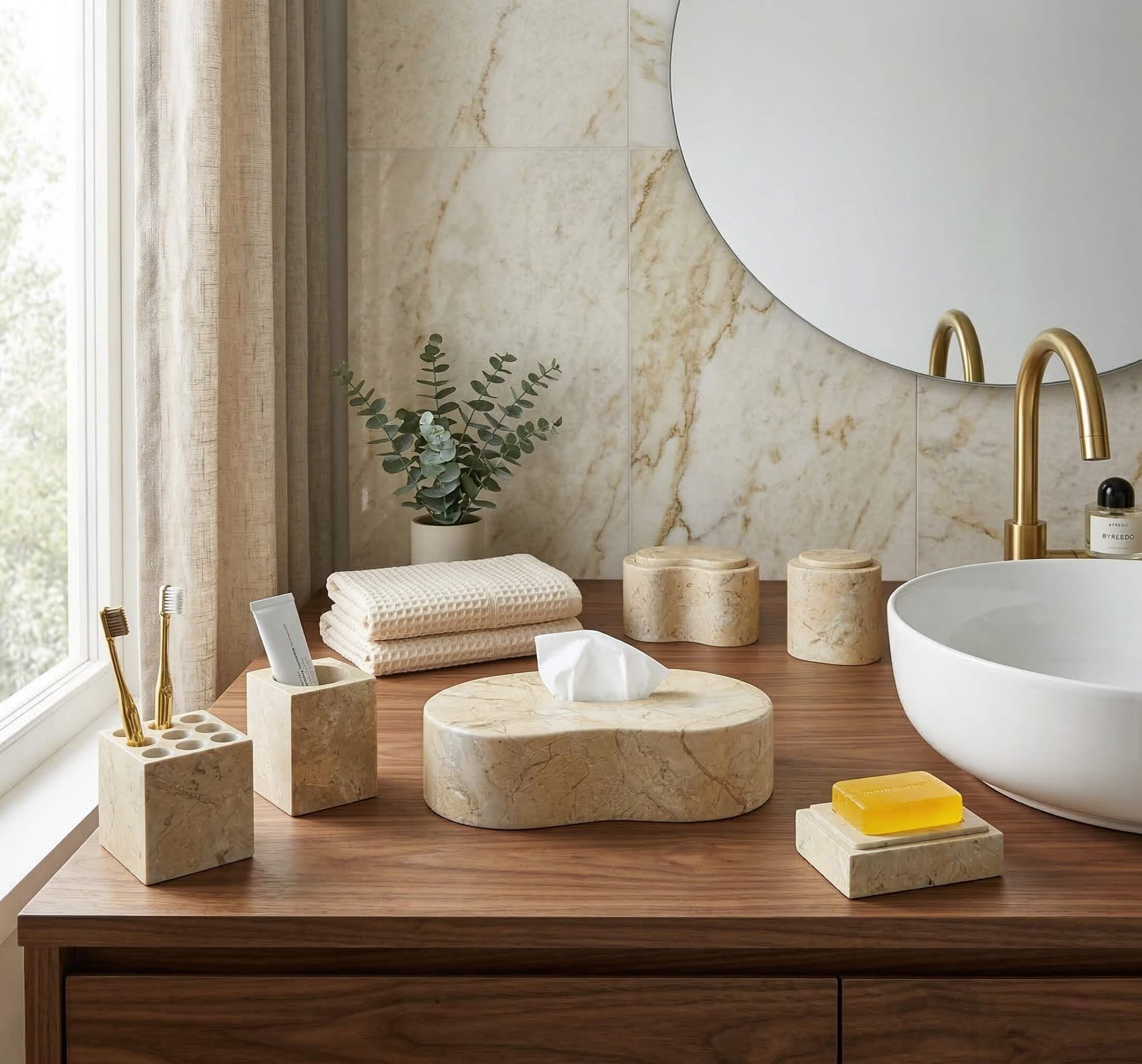 Amber gold natural marble vanity accessories set on a warm wood countertop next to a white porcelain vessel sink.